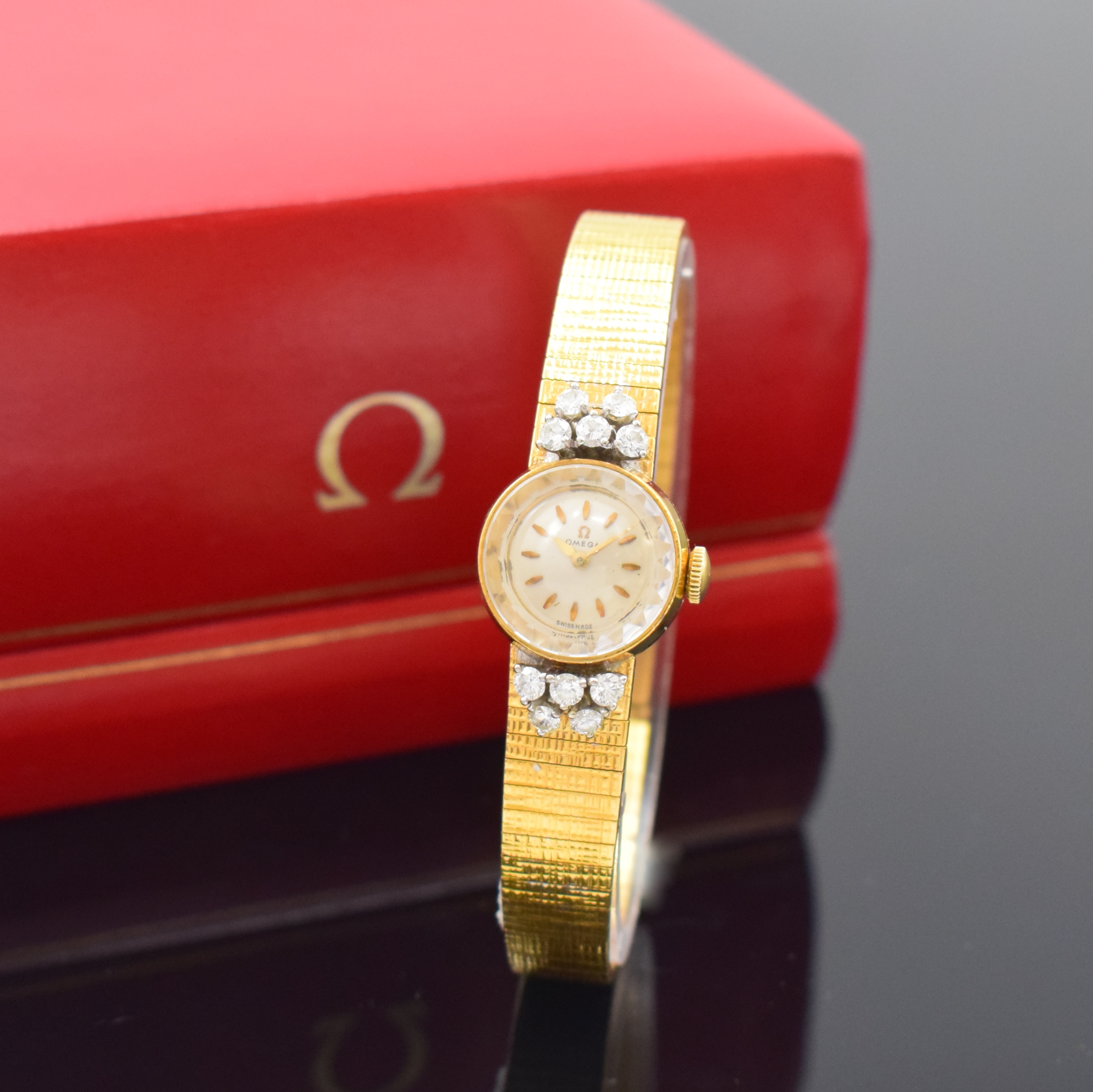 OMEGA Diamant-besetzte Damenarmbanduhr in GG 750/000, Schweiz um 1961, Handaufzug, Geh. m. anges. Band, Boden aufgedr., silb. Zifferbl., aufges. ...