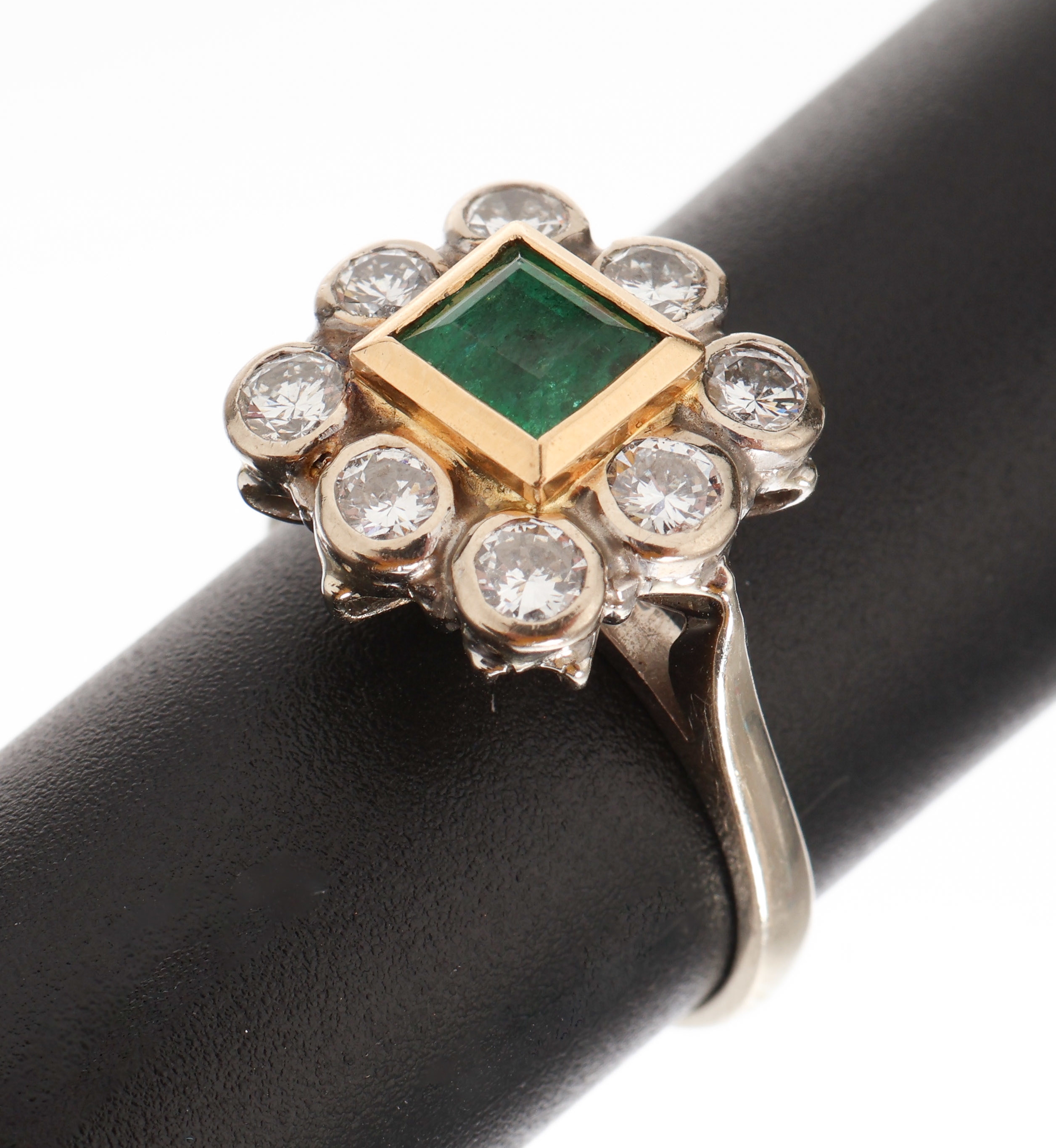 18 kt Gold Smaragd-Brillant-Ring, WG/GG 750/000, ein in GG gefasster Smaragd im Treppenschliff ca. 0.60 ct, umgeben von 8 Brillanten zus. ca. 1.0 ct ...