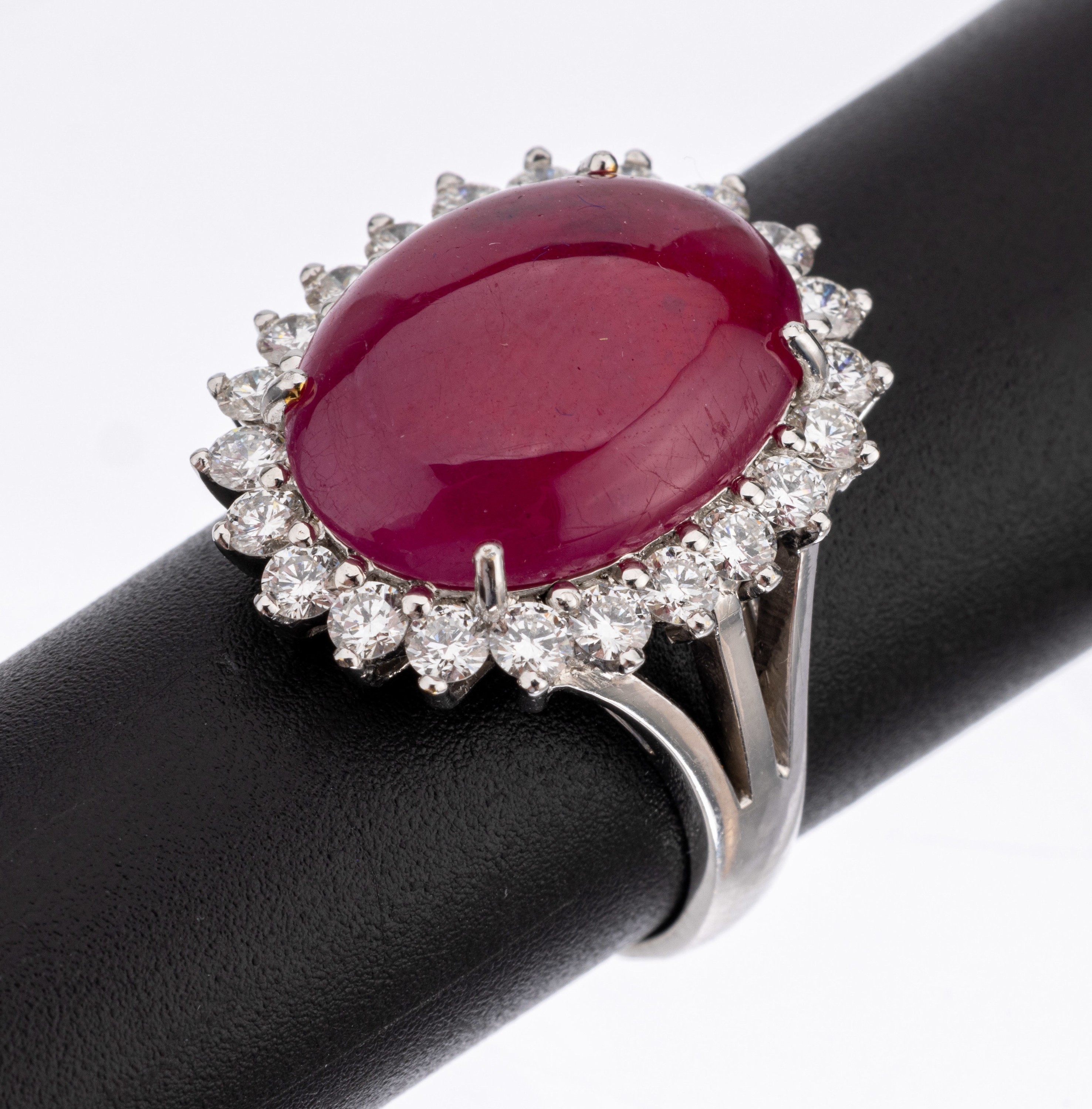 21.6 kt Gold Rubin Brillant Ring, WG 900/ 000, ovaler Rubincabochon ca. 12.0 ct (beh.) umgeben von 22 Brillanten zus. ca. 1.00 ct Weiß/vs-si, RW ...