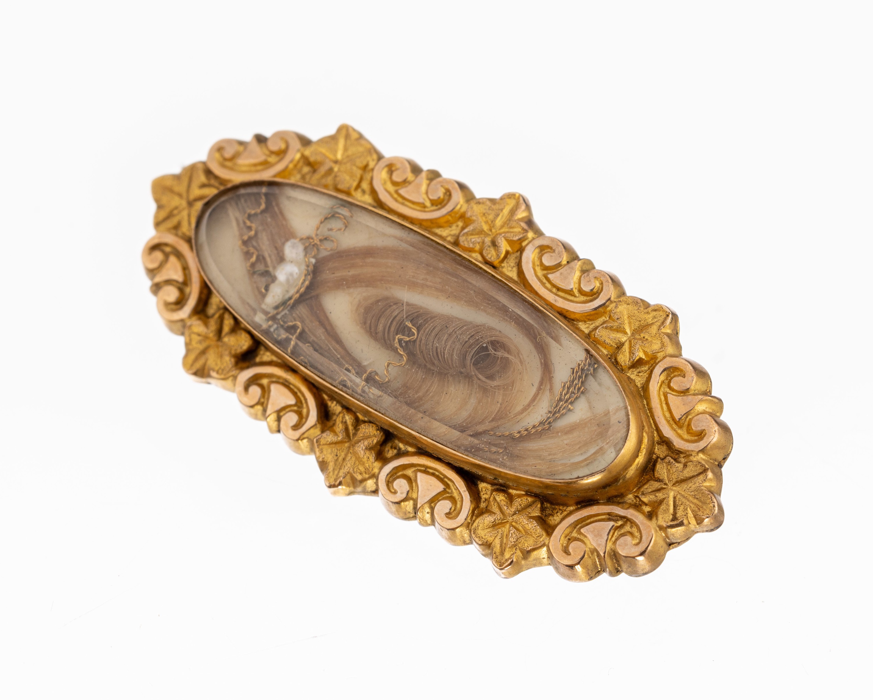 9 kt Gold Brosche, England um 1890, GG 375/000, länglich oval, mittig hinter Bergkristall Haarsträhnen, Rahmung mit Volutenund Efeublätter, L. ...