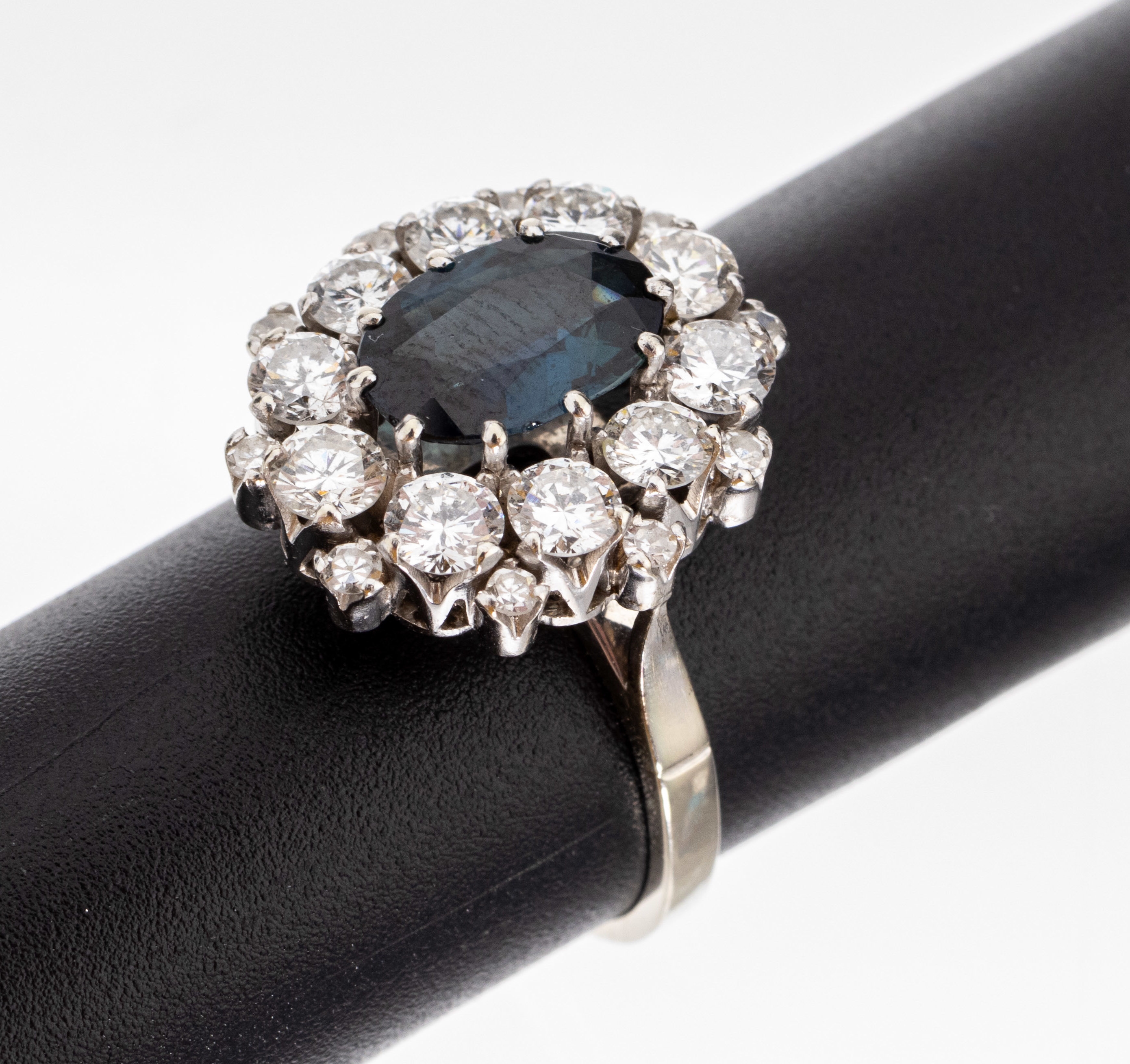 18 kt Gold Saphir-Brillant-Ring, WG 750/000, ovalfacett. Saphir ca. 1.80 ct, umgeben von 10 Brillanten und 10 kl. 8/8- Diamanten zus. ca. 1.70 ct ...