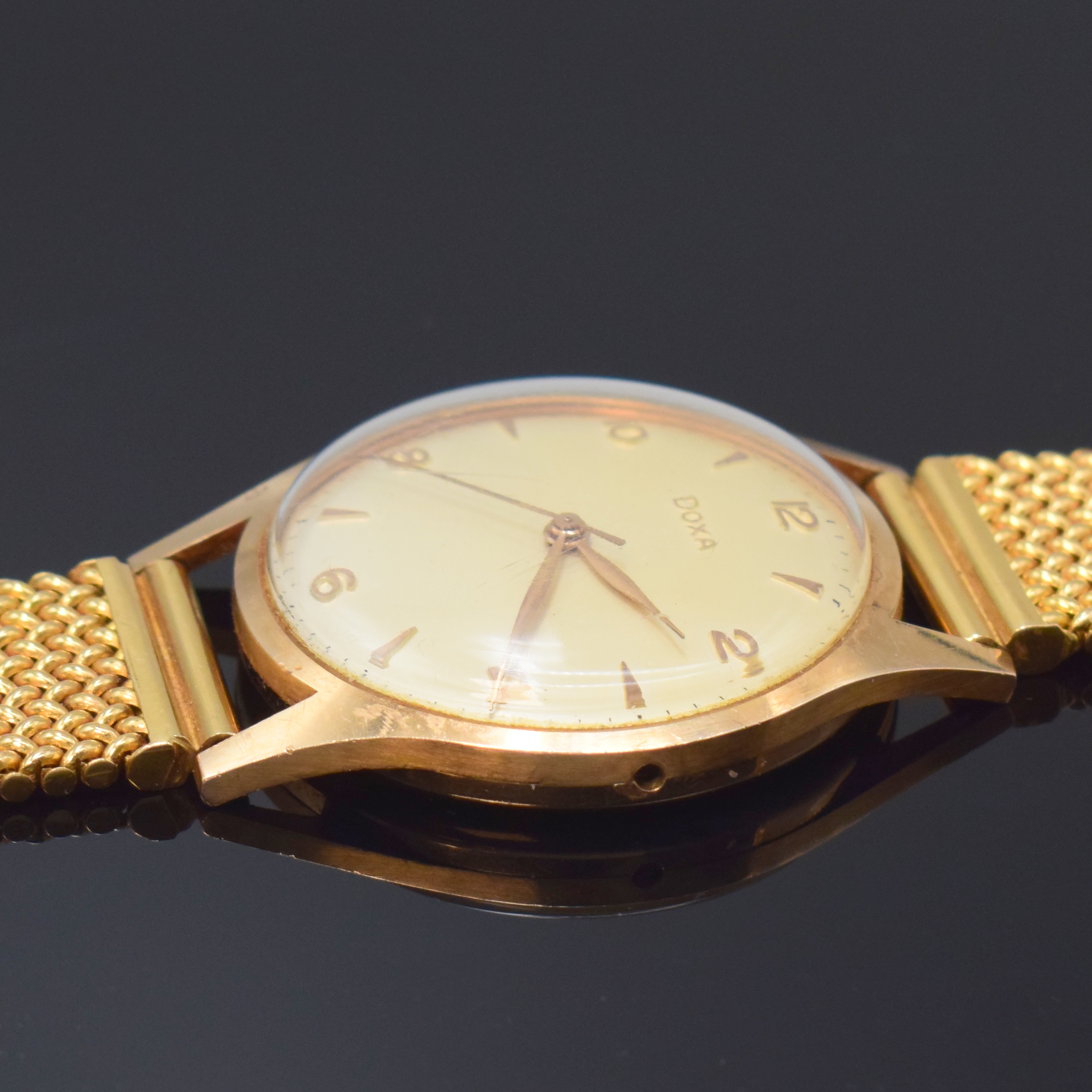 Detail c: DOXA Herrenarmbanduhr in RG 585/000, Schweiz um 1965, Handaufzug, neutr. RG 750/000 Band, Boden aufgedr., silb. Zifferbl. m. arab. Zahlen u. gold. ...