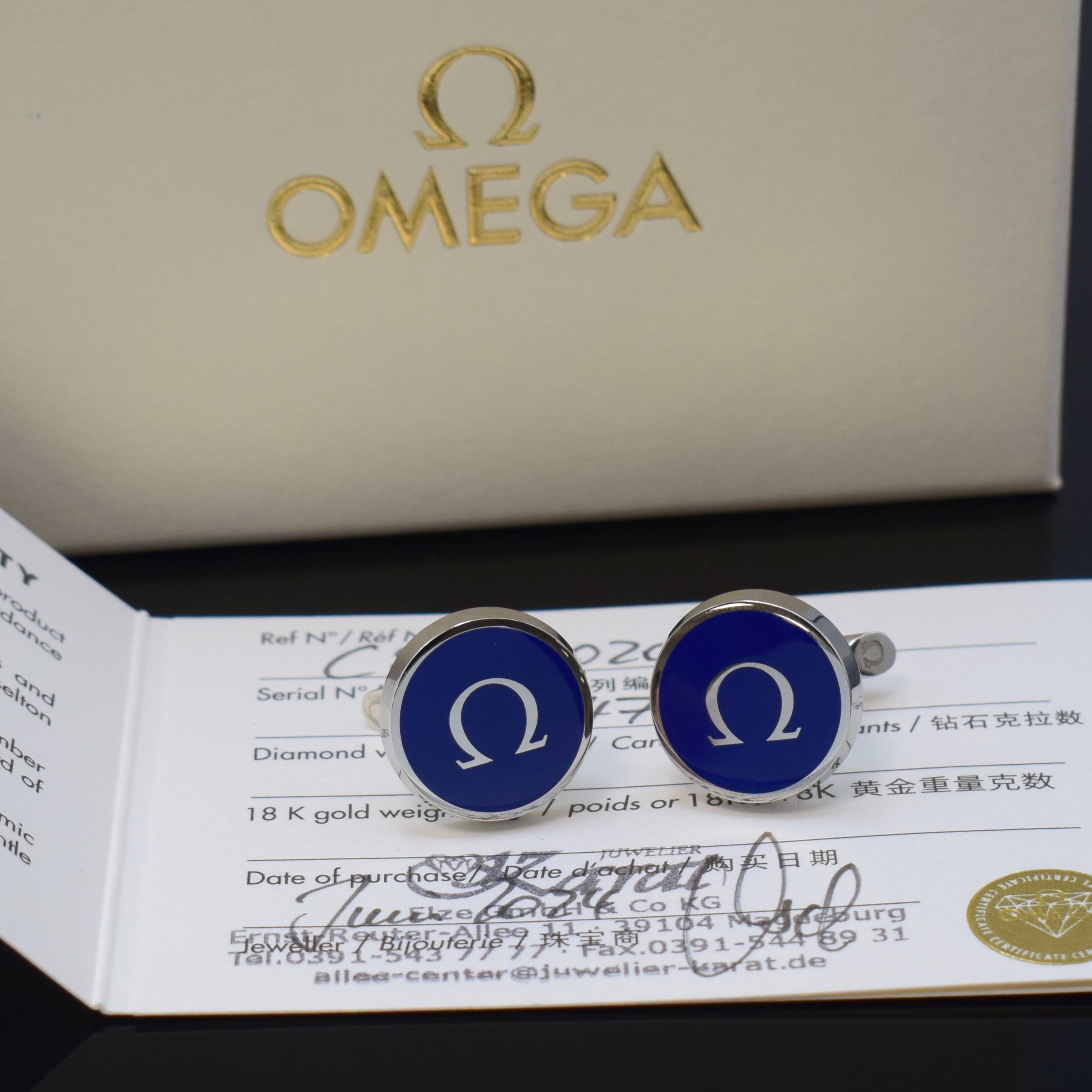 OMEGA Manschettenknöpfe in Edelstahl mit original Etui und Zertifikat, verk. lt. beil. Zertifikat 06/2024, blauer Lack, Kippverschluss, M. ca. 20 x ...