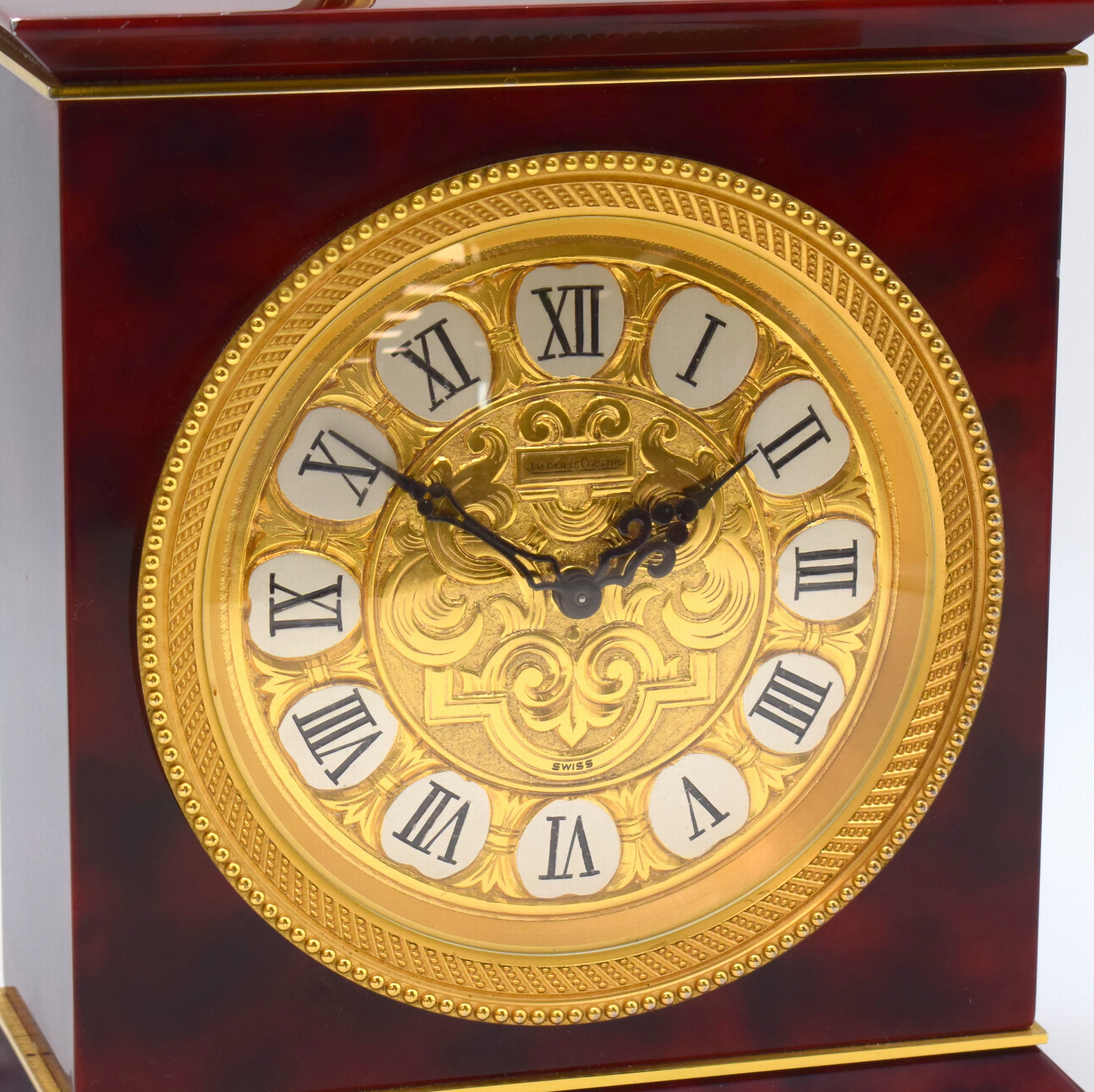 Detail a: Jaeger-LeCoultre Tischuhr mit 1/2- Stundenschlag im Chinalack-Gehäuse Referenz 5507, Schweiz um 1960, rot marmoriert. Geh. m. Tragegriff, massive ...