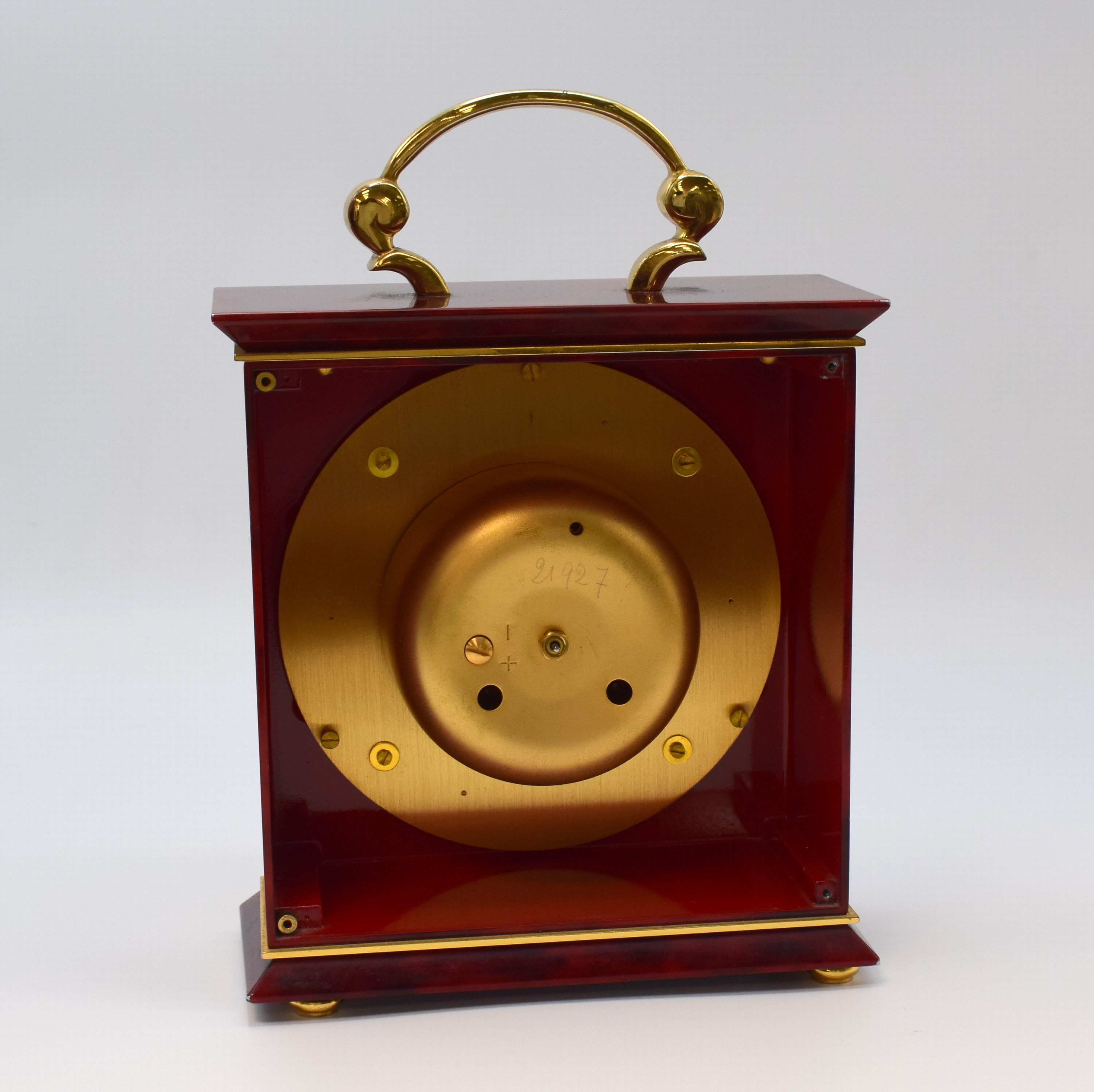 Detail e: Jaeger-LeCoultre Tischuhr mit 1/2- Stundenschlag im Chinalack-Gehäuse Referenz 5507, Schweiz um 1960, rot marmoriert. Geh. m. Tragegriff, massive ...