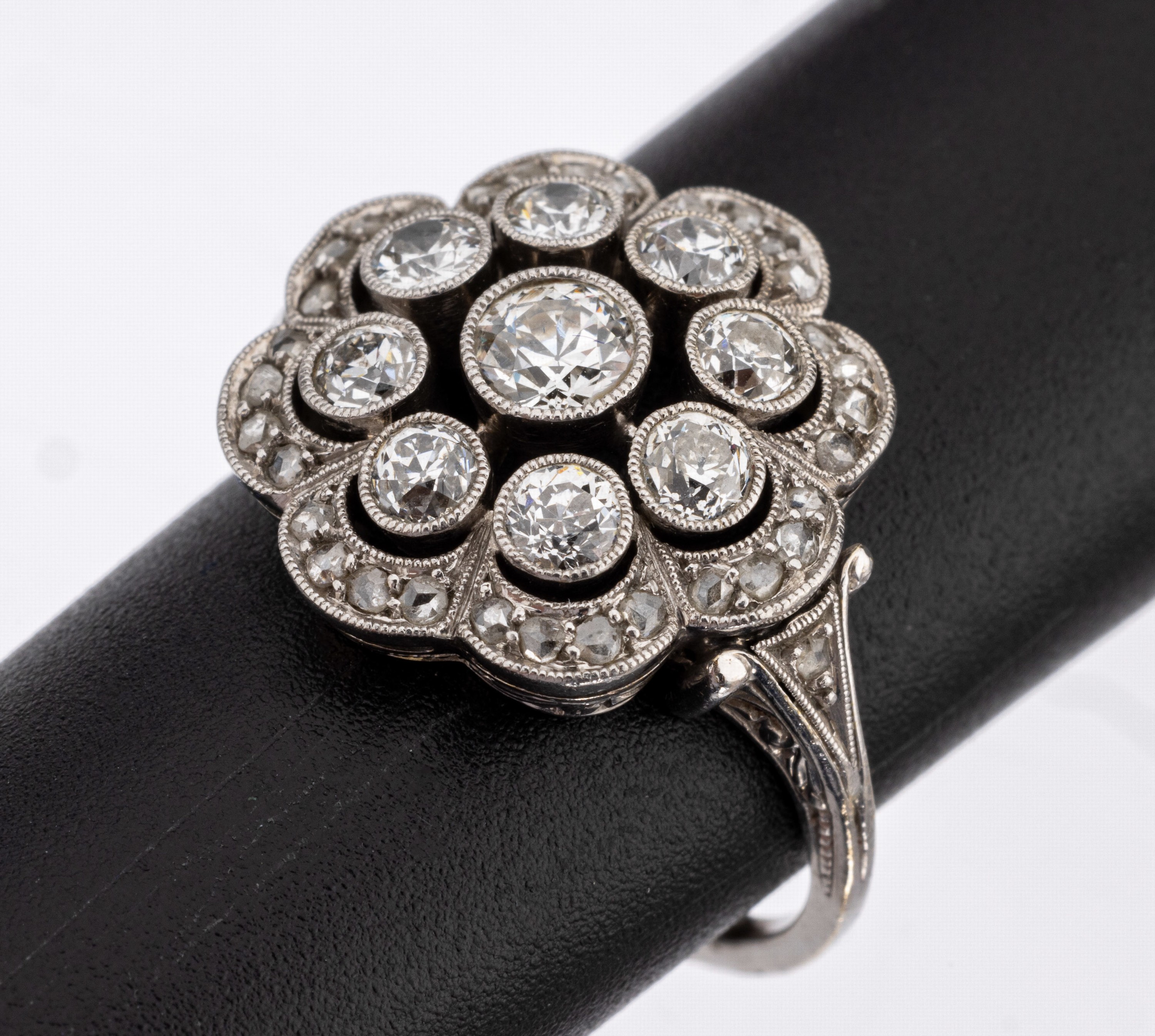 Platin Diamant Ring, deutsch um 1910/20, Pt. gepr., blütenf. Ringkopf 3 Ebenen, bes. mit 9 Altschliffdiamanten zus. ca. 0.60 ct Weiss/si, umgeben ...