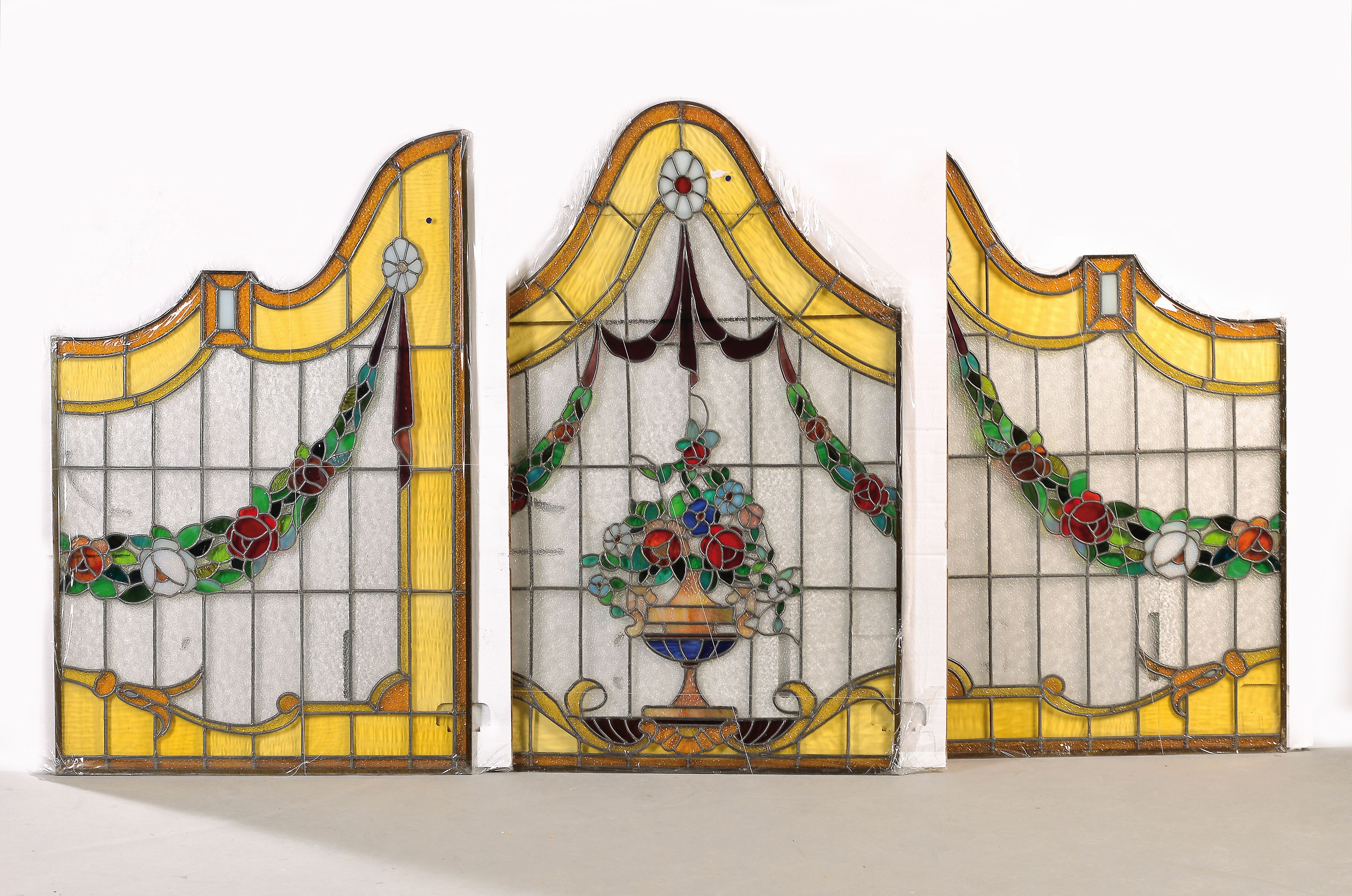 3 teilige Bleiglasfenster-Garnitur, Belgien, Anfang 20.Jh., farbloses und buntes Glas in leuchtenden Farben, geschweifte Form, Dekor mit ...
