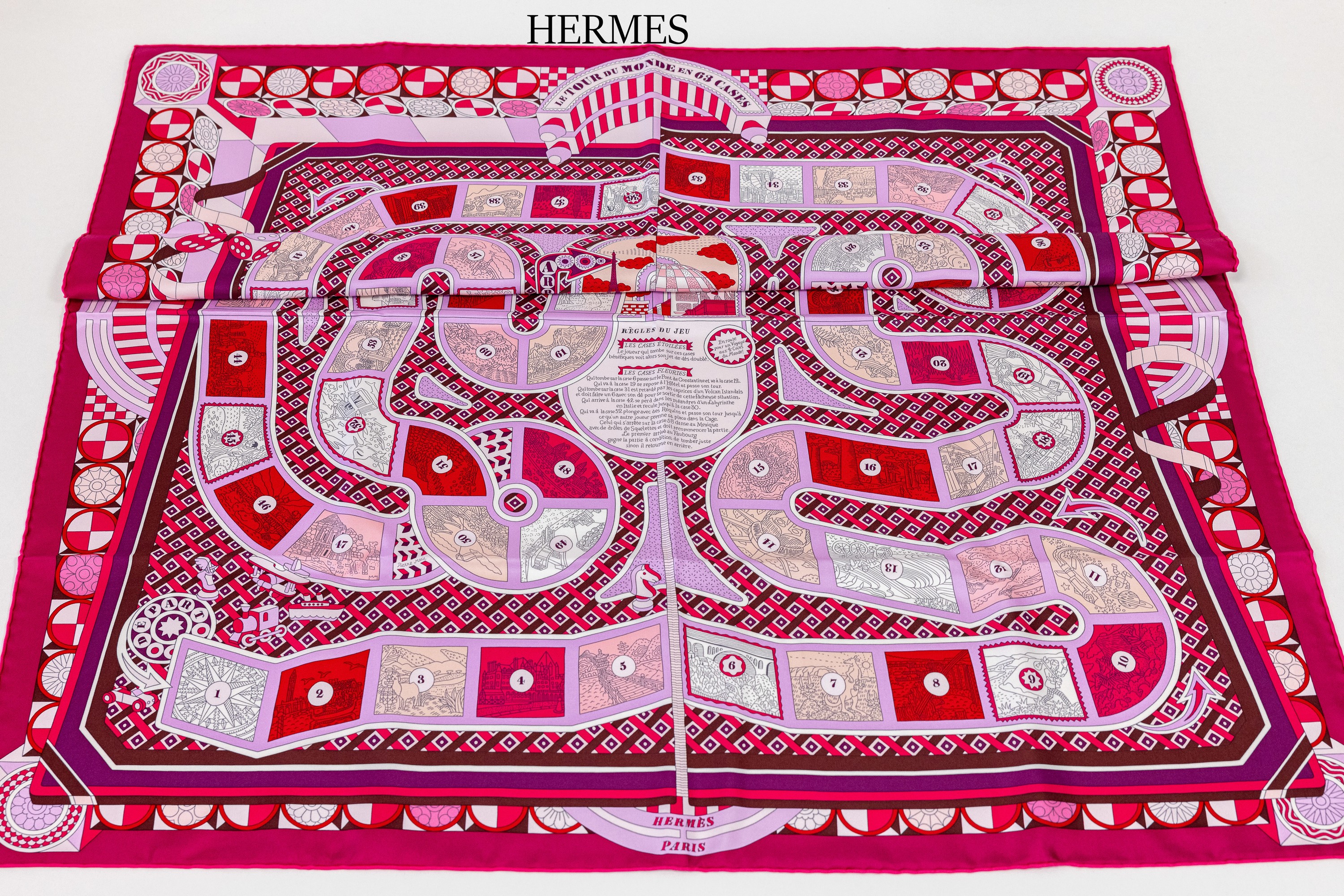 Hermes Seidencarree Le Tour du Monde en 63 Cases, Design Pierre Marie 2018, fuchsia- farbener Seidenkörper mit Motiven in Rot, Creme, Pfirsich, ...