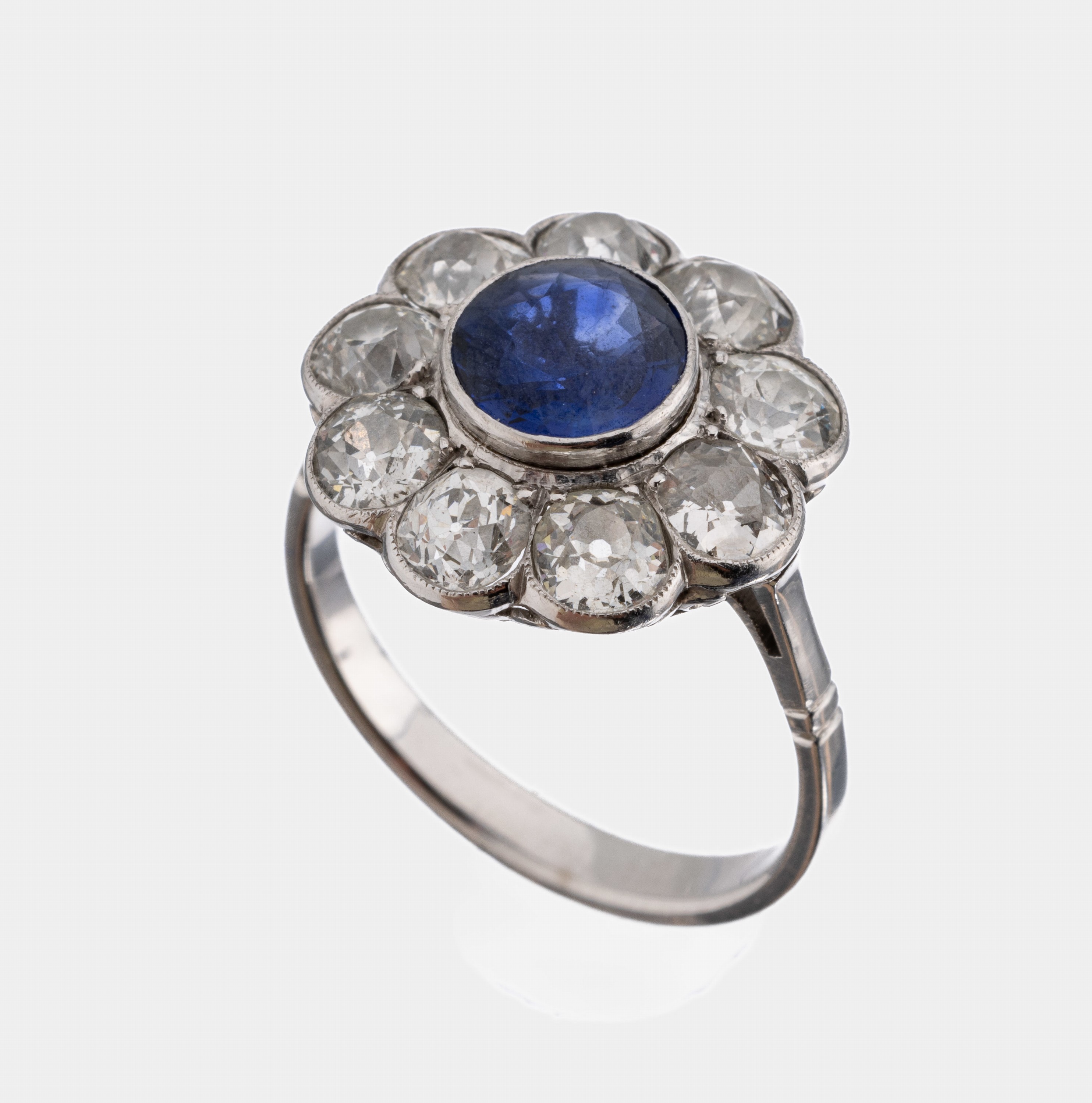 18 kt Gold Saphir-Diamant-Ring, WG 750/000,blütenförm. Ringkopf, rundfacett. Saphir ca. 2.0 ct, umrahmt von 9 Altschliffdiamanten zus.ca. 3.20 ct ...