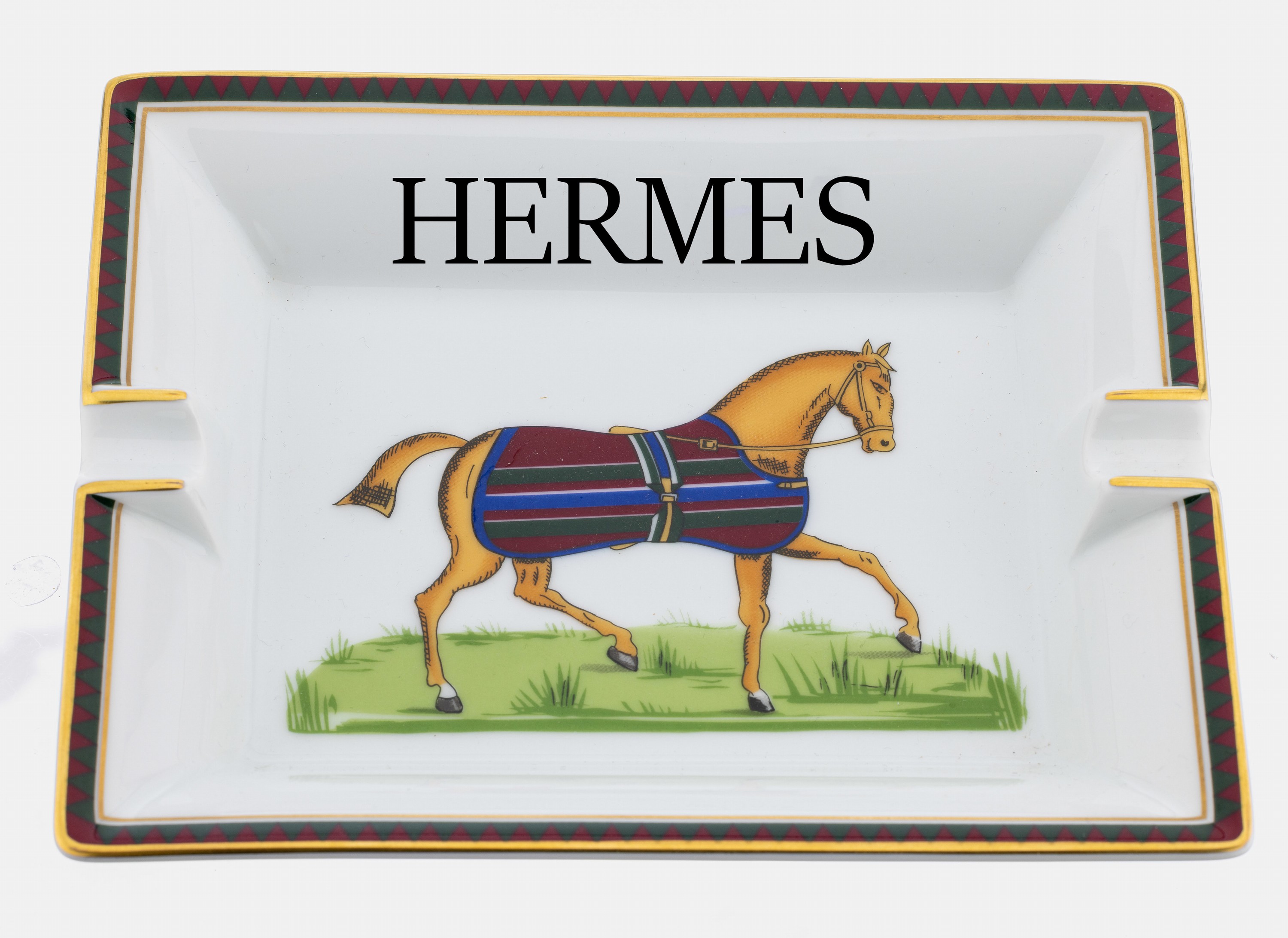 Hermes Aschenbecher, Porzellan, Darstellungeines Pferdes mit gestreifter Decke, Zierrand mit roten Dreiecken auf dunkelgrünem Rand, ca.9 x 5.5 cm, ...