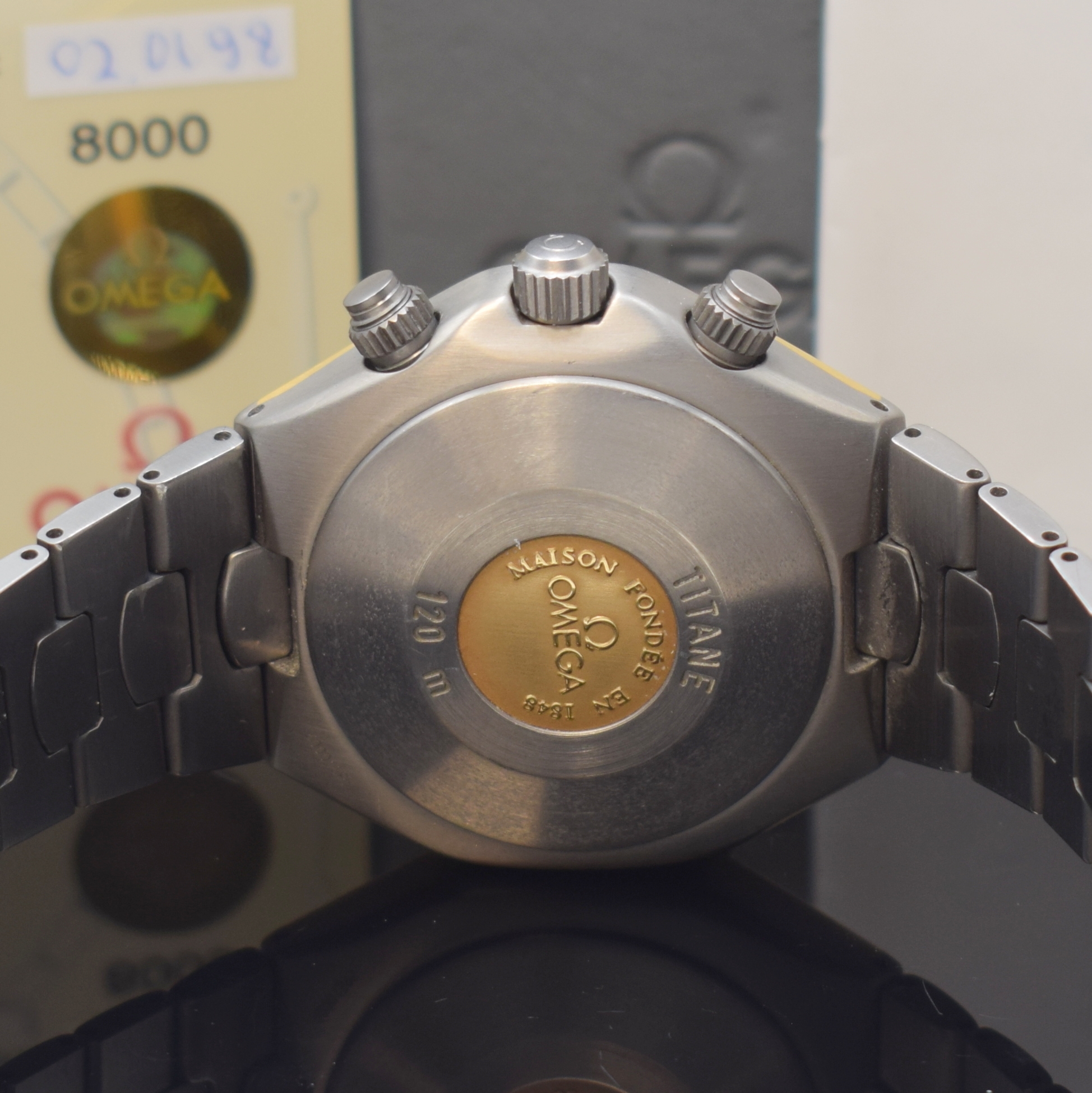 Detail d: OMEGA Armbandchronograph Titane Referenz 58944000, Automatik, Chronometer in Titan inkl. Titanband m. dopp. Faltschl., Boden m. Goldlogo aufgedr., ...