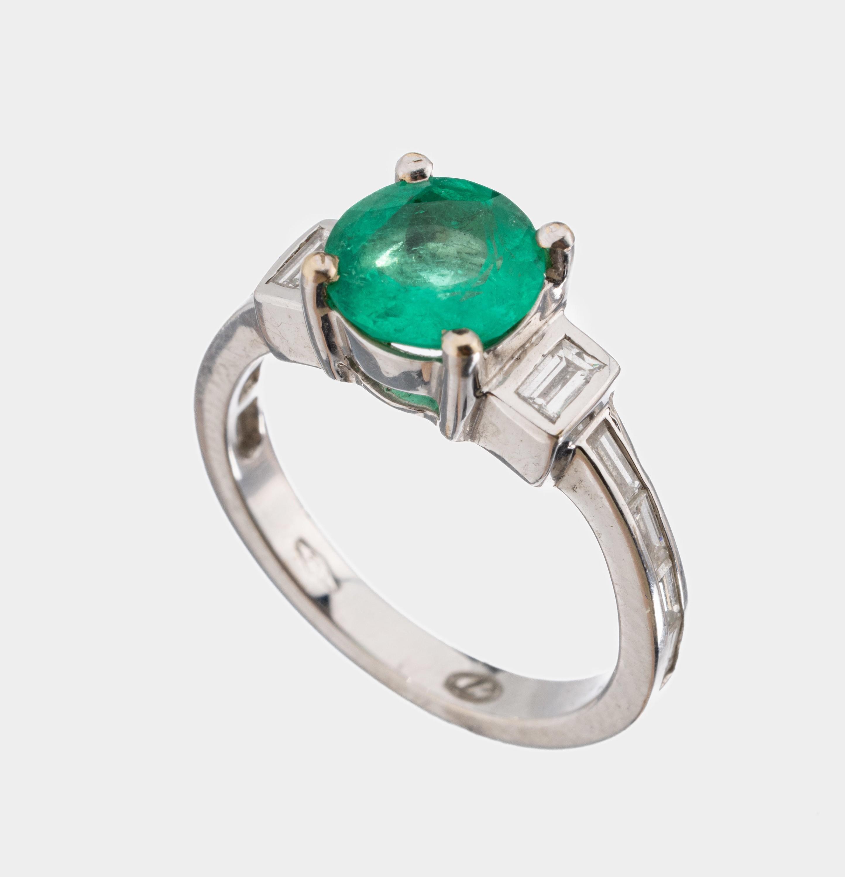 18 kt Gold Smaragd-Diamant-Ring, WG 750/000, mittig erhaben gefasster rundfacett. Smaragd ca. 1.00 ct, 10 Diamant-Baguettes zus.ca. 0.50 ct ...