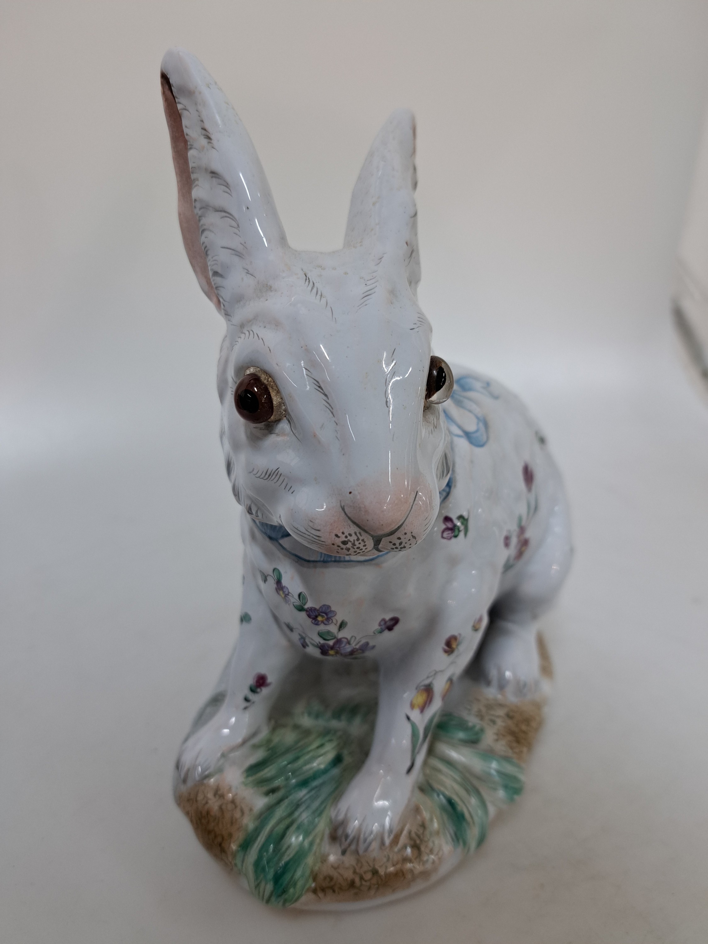 Detail b: Keramikfigur/sitzender Hase, Emile Gallé, Fayencerie de Nancy, Keramik, helle Zinnglasur reich bemalt mit Blumen und blauer Schleife, Sockel ...