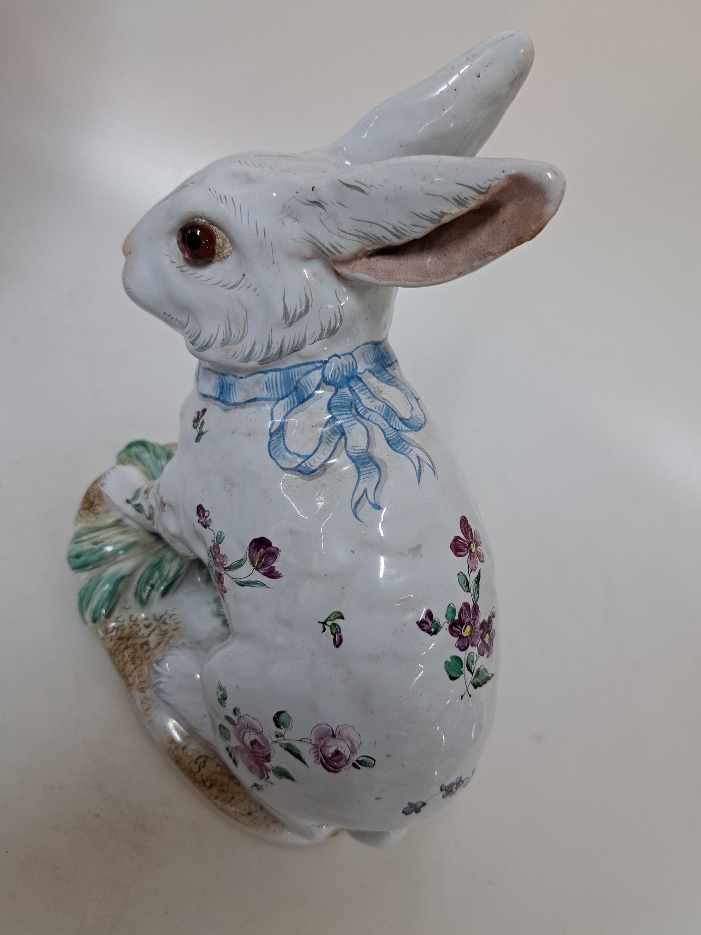 Detail c: Keramikfigur/sitzender Hase, Emile Gallé, Fayencerie de Nancy, Keramik, helle Zinnglasur reich bemalt mit Blumen und blauer Schleife, Sockel ...