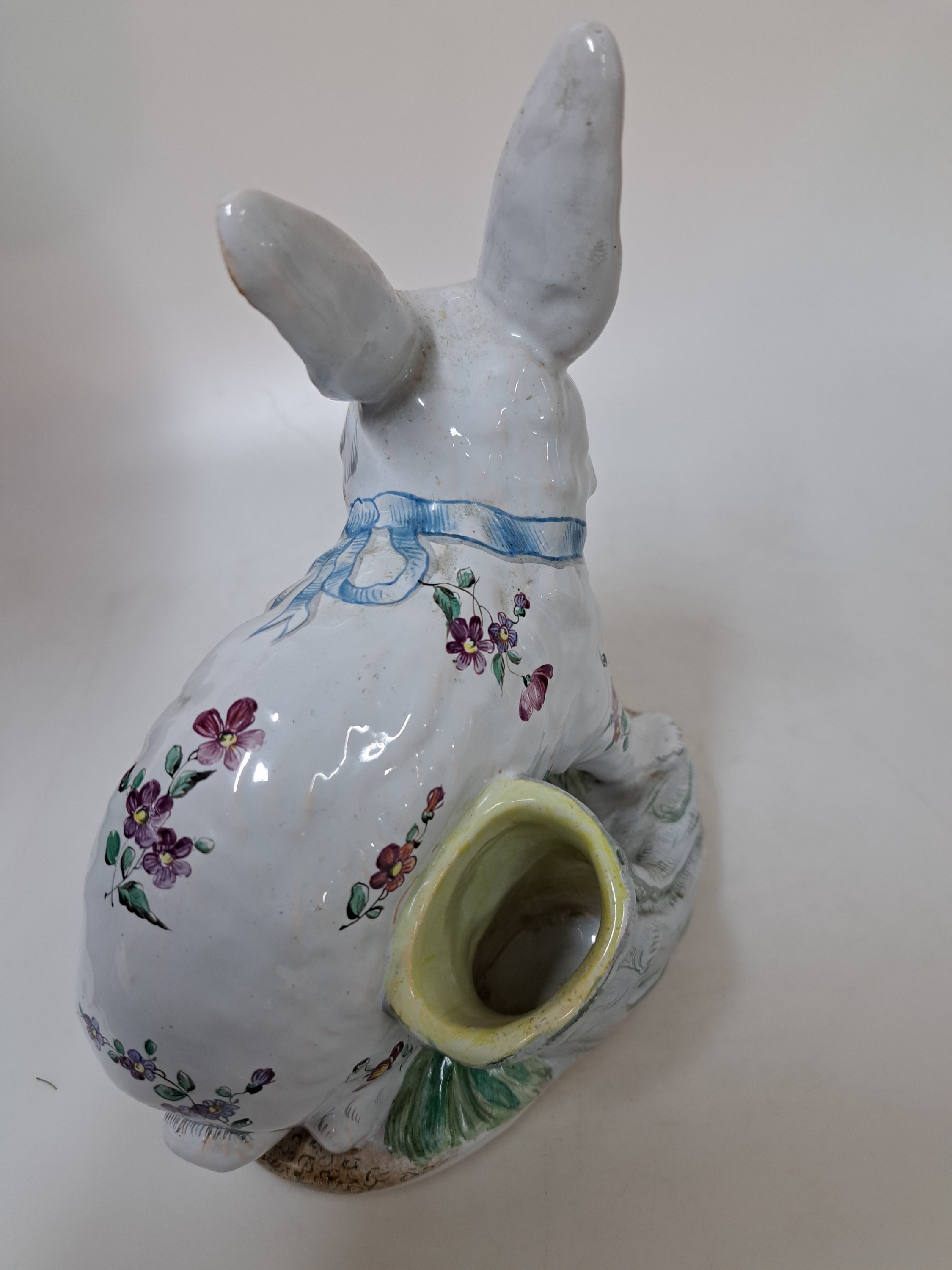 Detail g: Keramikfigur/sitzender Hase, Emile Gallé, Fayencerie de Nancy, Keramik, helle Zinnglasur reich bemalt mit Blumen und blauer Schleife, Sockel ...