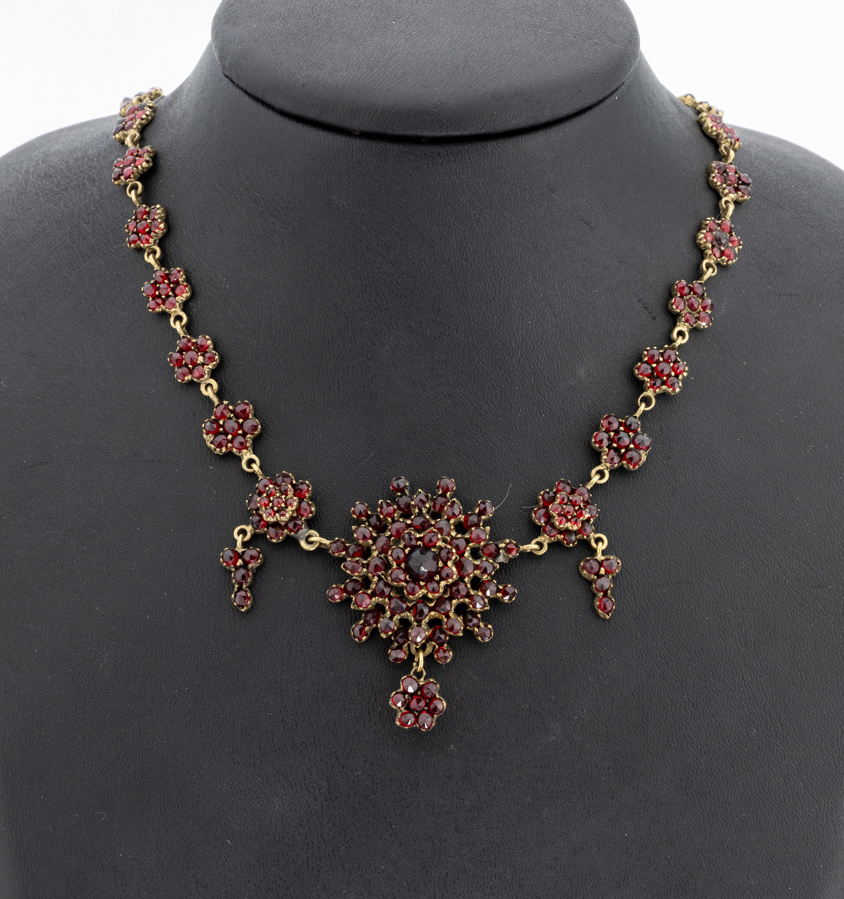 Granatcollier, Tombak verg., Böhmen um 1910, blütenförm. Elemente mit rundfacett. Granaten, bewegl. Abhängungen, L. ca. 50 cm, ...