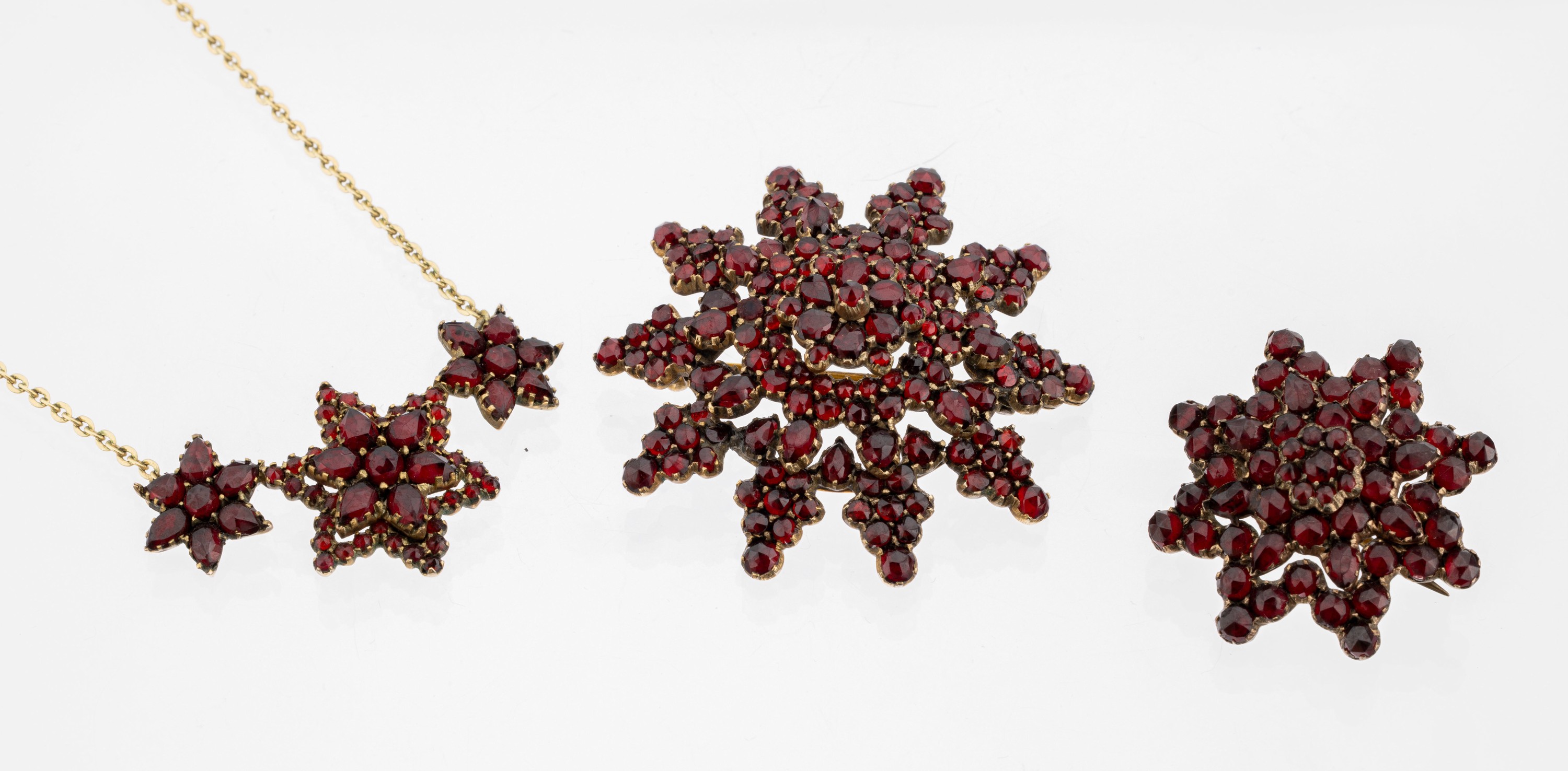 Konvolut Granat-Schmuck, Tombak verg., Böhmen um 1910, best. aus: 1 x Collier, Mittelteil mit sternförm. Elementen, rundfacett. Granate, Kette ...