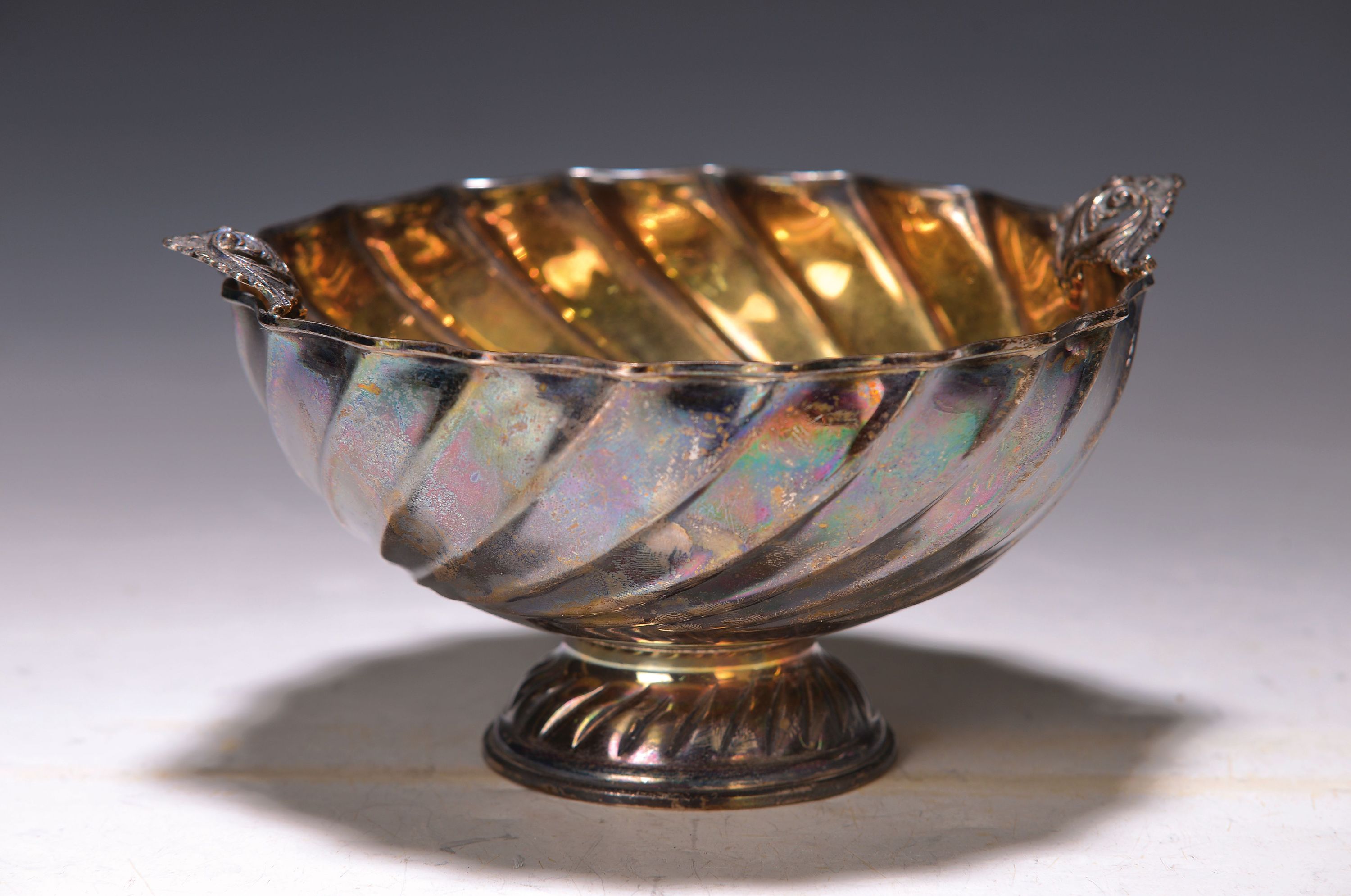 Fußschale, wohl Italien, 20. Jh., 900er Silber, innen vergoldet, gedrehte Form, zwei stil. Henkel im Akanthusblattdekor, ca. 205 g, H. 9 cm