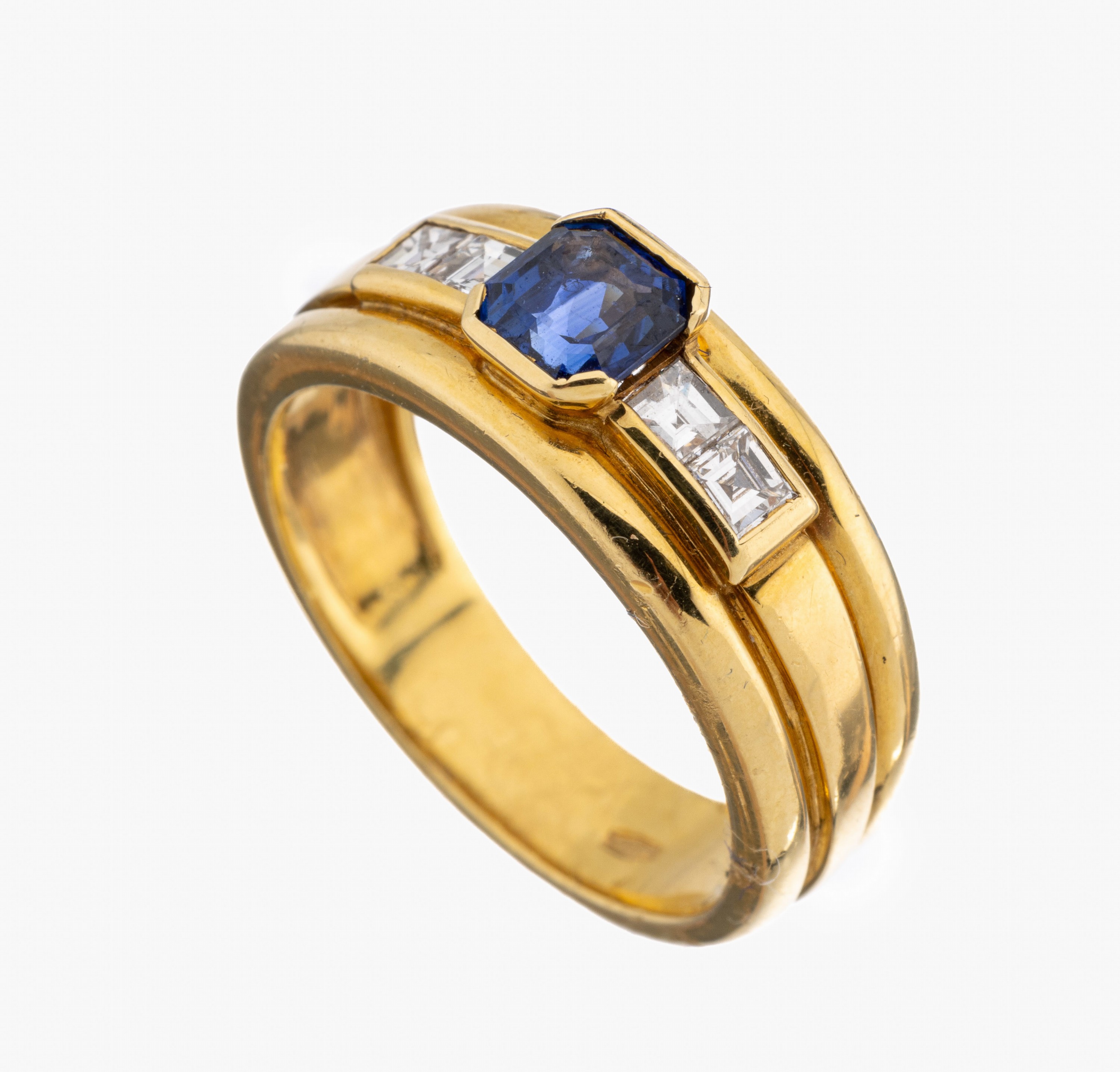 18 kt Gold Saphir-Diamant-Ring, GG 750/000,facett. Saphir ca. 0.70 ct, von schöner Farbe,seitl. flankiert von 4 Diamantcarrees zus. ca.0.20 ct ...