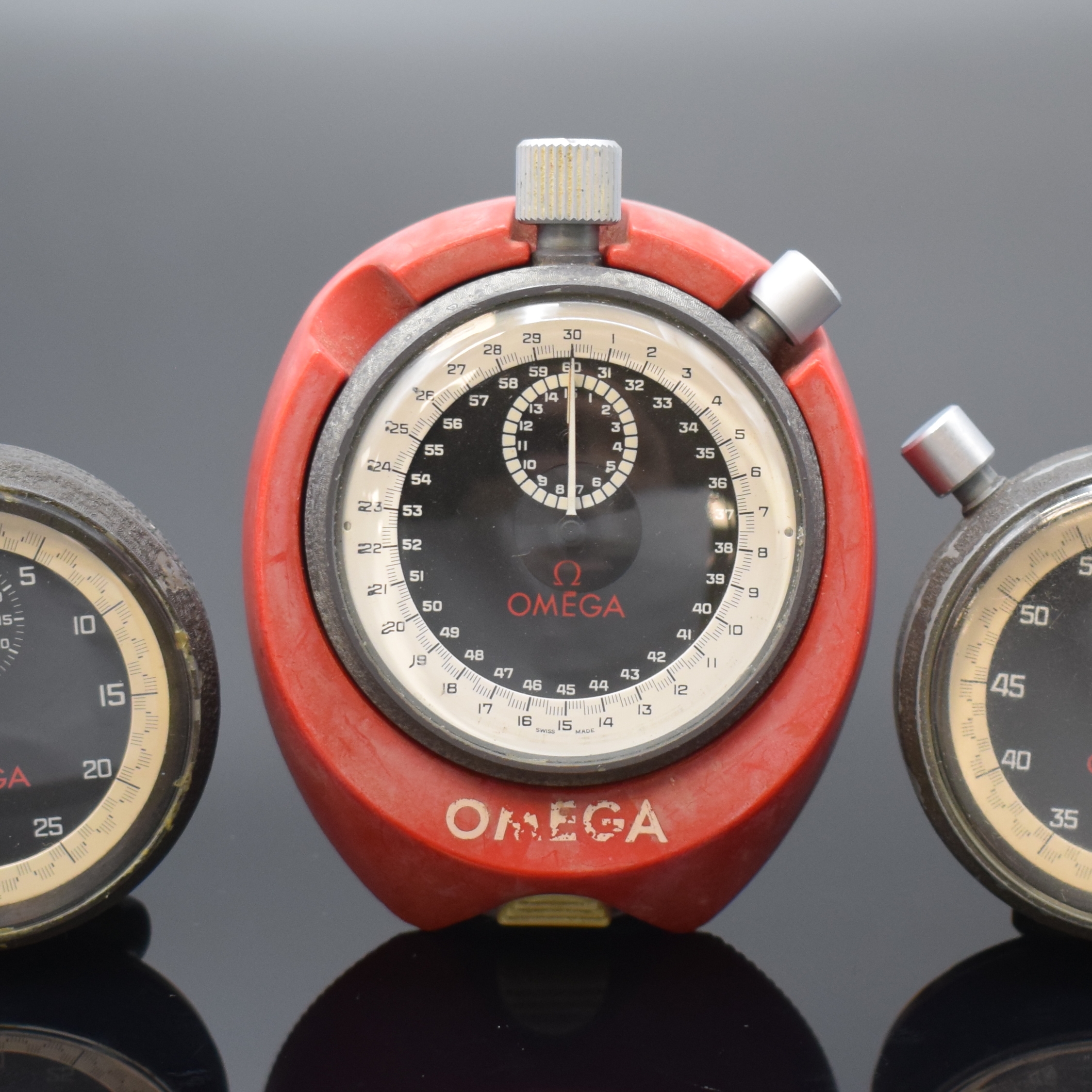 Detail a: OMEGA 3 Stoppuhren, Schweiz um 1965, Handaufzug, Metallgeh., schwarz lack. berieb., verschr. Stahlböden, schwarz. Zifferblätter m. weißer ...