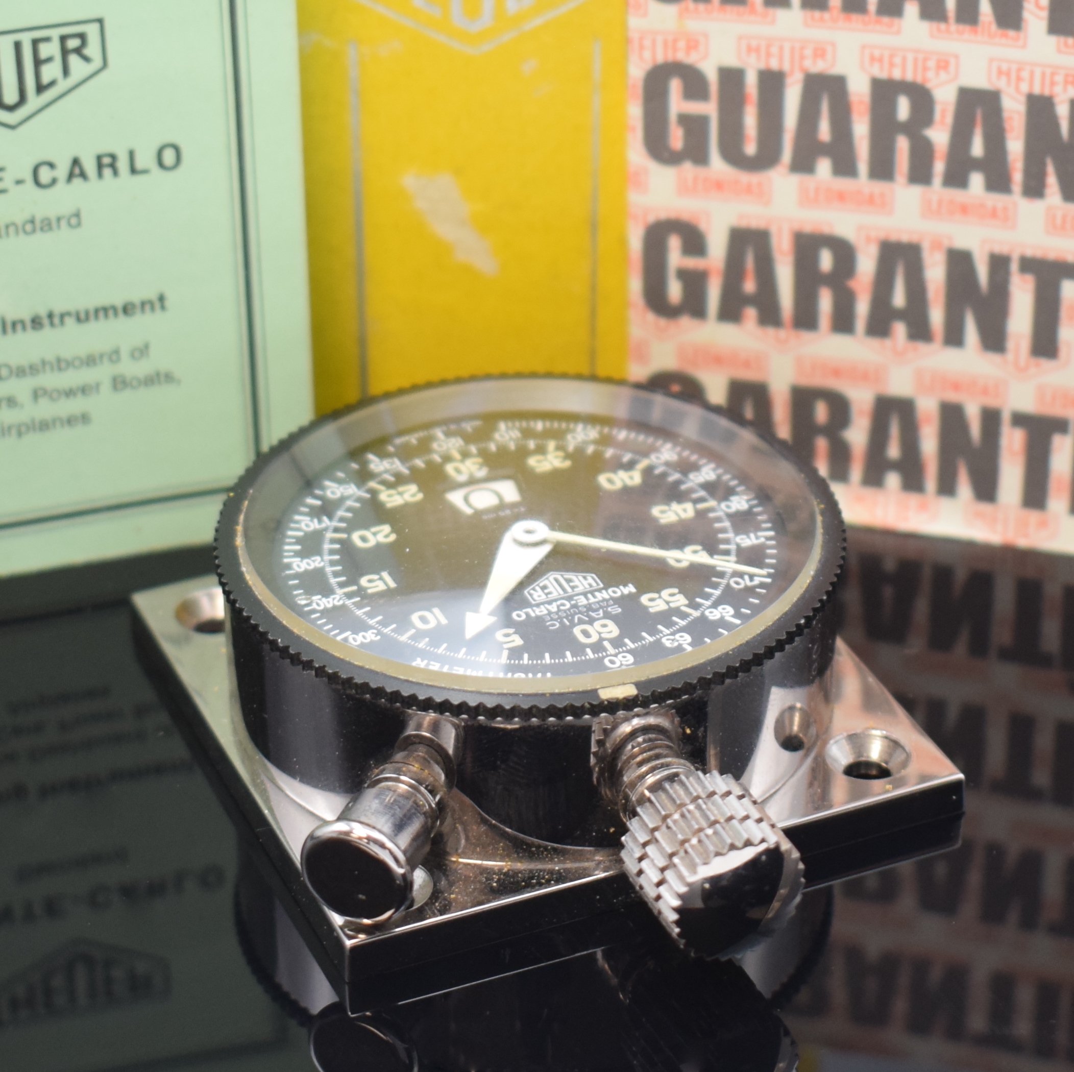 Detail a: HEUER Monte Carlo Dashboard Nr. 55990 Referenz 16.8433, Schweiz um 1960, verchr. Metallgeh. montiert auf quadratischer Metallplatte, schwarze ...