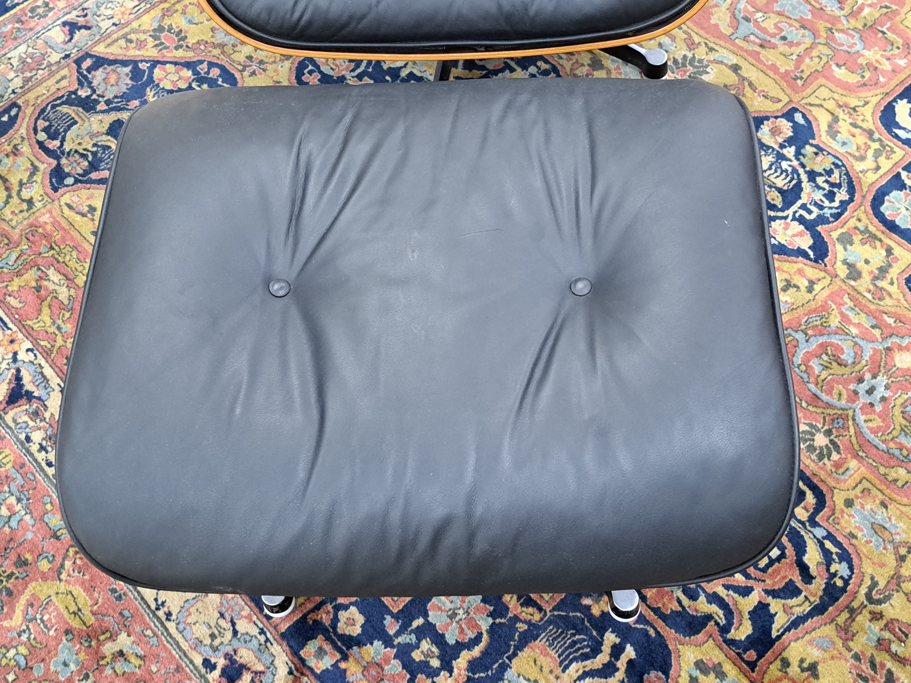 Detail b: Lounge Chair mit Ottomane, Entwurf Charles und Ray Eames, Ausführung Vitra, Entwurf von 1956, Polsterung im schwarzen Leder, diese vor 10 Jahren ...