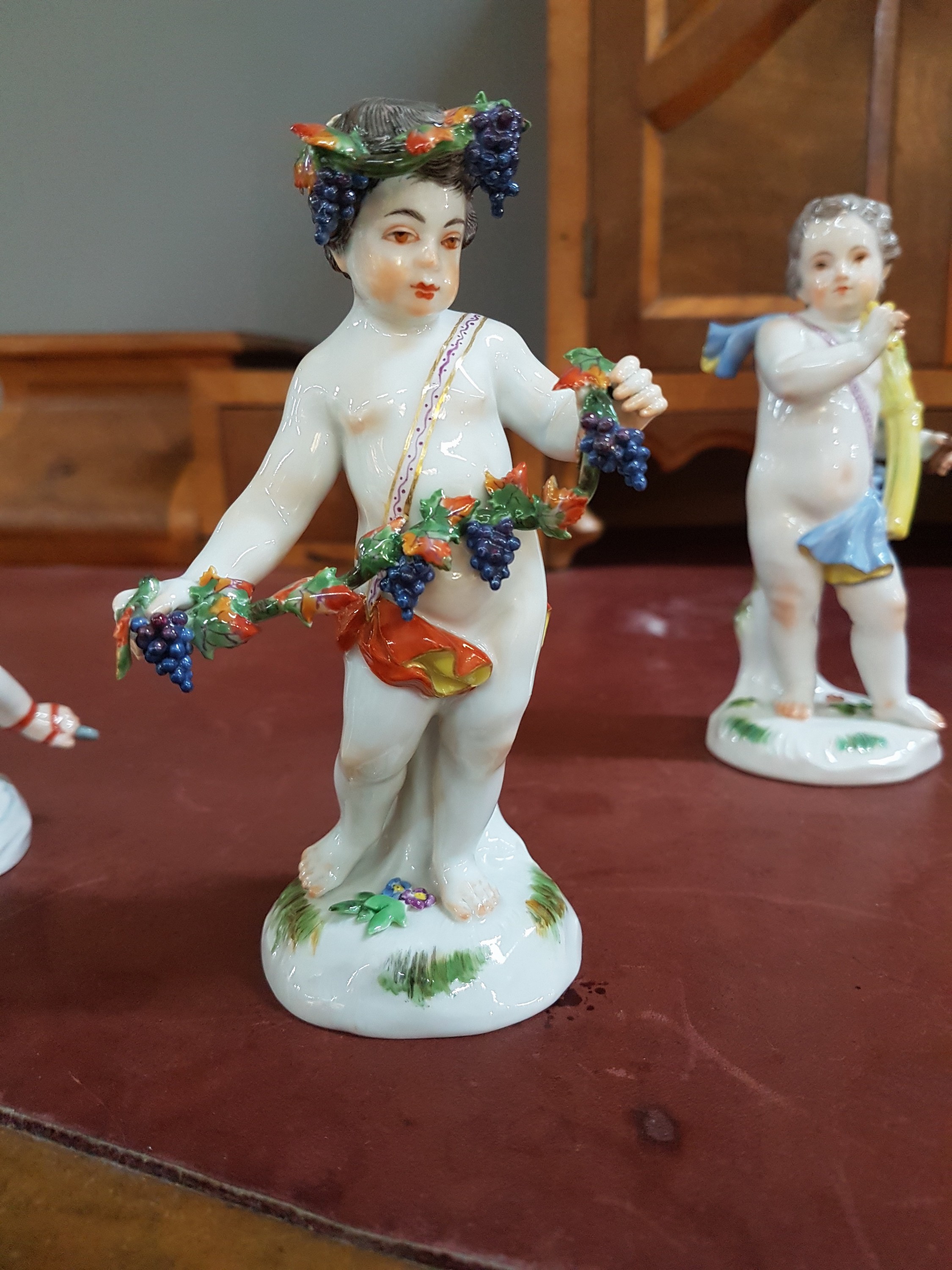 Detail c: 4 Porzellanfiguren, Meissen, 20. Jh., Allegorien auf die vier Jahreszeiten, Amoretten mit Blumen, Ähren (Sichel abgebrochen, aber vorhanden), ...