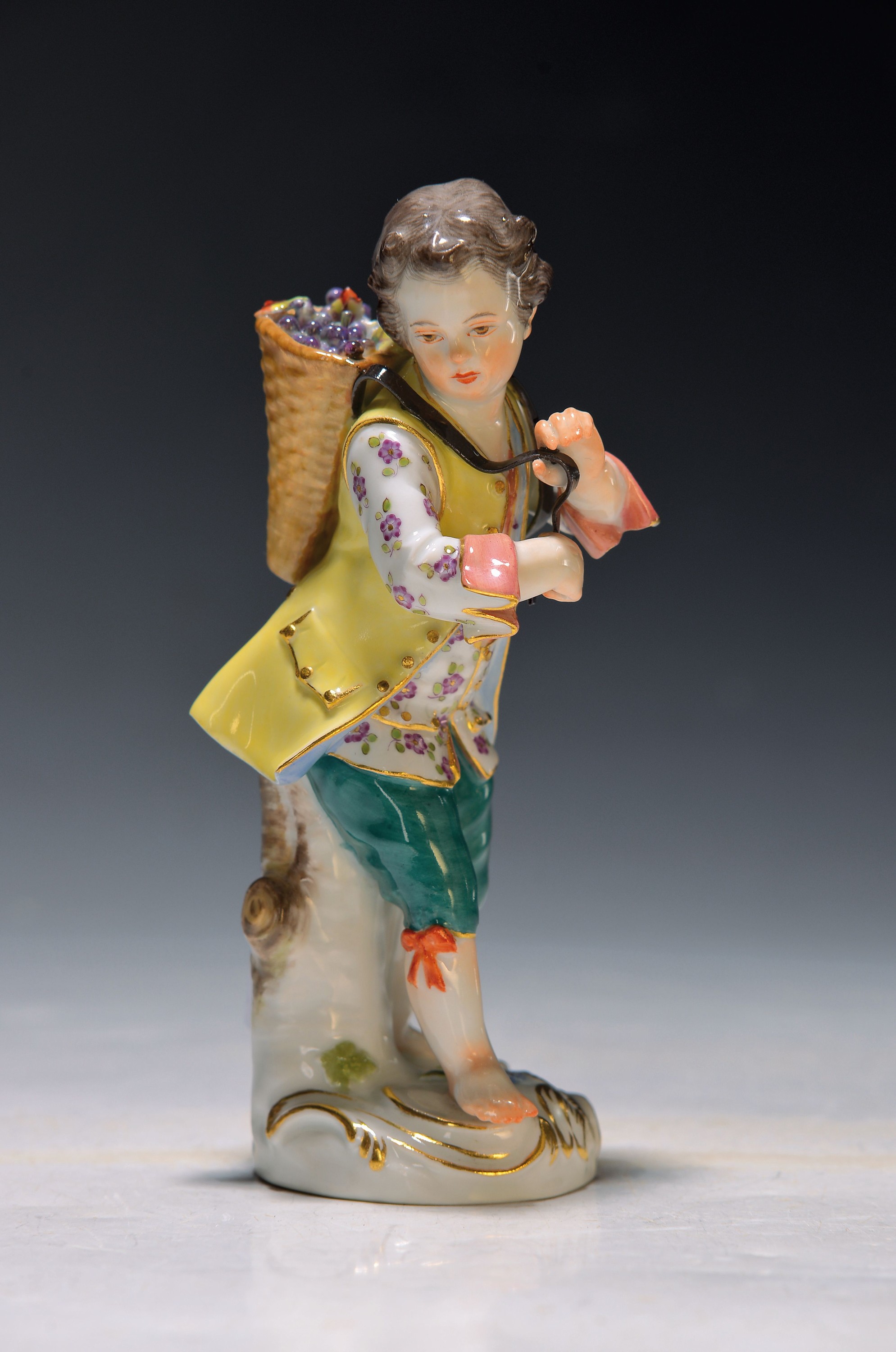 Porzellanfigur, Meissen, 20. Jh., 1. Wahl, Junger Winzer mit Traubenkiepe auf dem Rücken, bunt bemalt, Goldstaffage, H. ca. 13.5cm