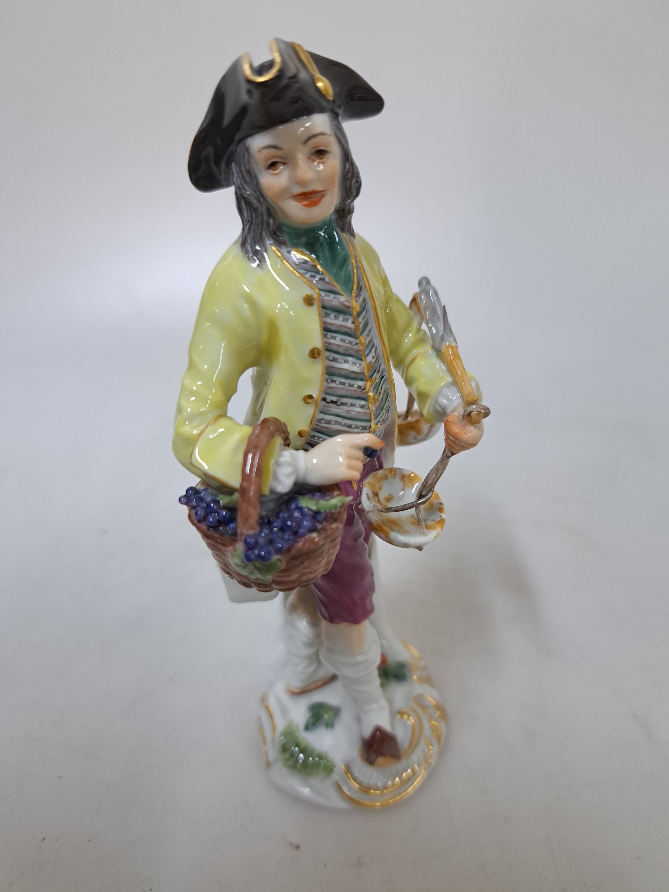 Detail b: Porzellanfigur, Meissen, 20. Jh., 1. Wahl, Mann mit Traubenkorb und Waage, bunt bemalt, Goldstaffage, H. ca. 14cm