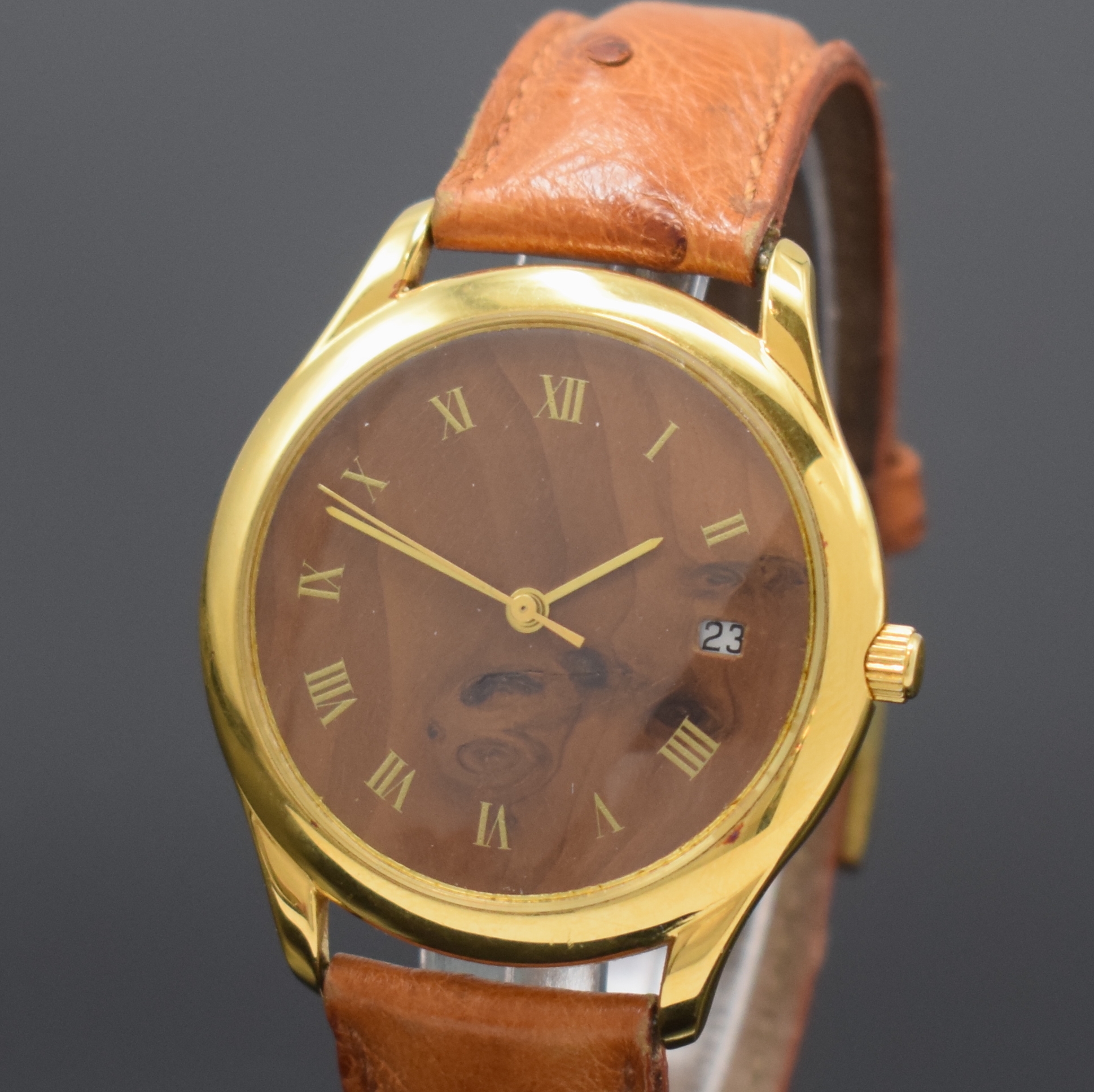 Detail a: Herrenarmbanduhr mit Nussbaum-Zifferblatt, Schweiz um 1990, Automatik, beids. vergl. Geh. verg., Nussbaum-Zifferbl. m. röm. Zahlen, gold. Zeiger, ...
