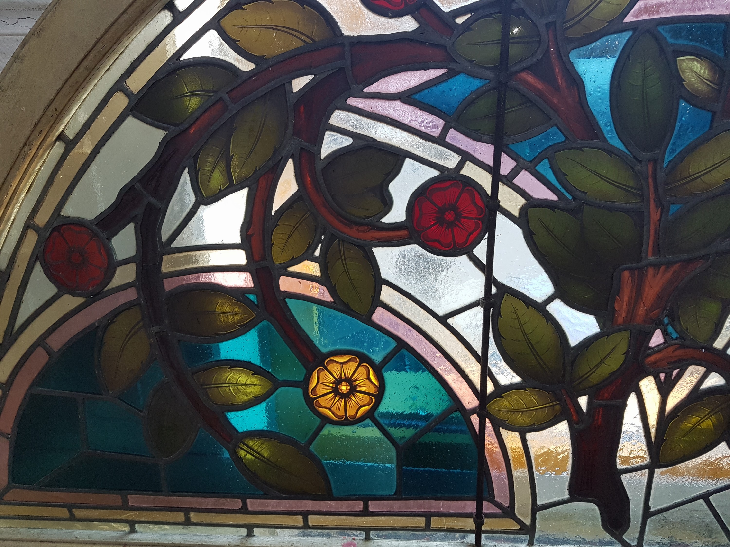 Detail c: Bleiglasfenster, wohl Belgien, um 1900, farbiges Glas mit Blei-Stegen, Holzrahmen, Blütenzweigdekor, bogenförmig als Kämpferfenster verwandt, ...