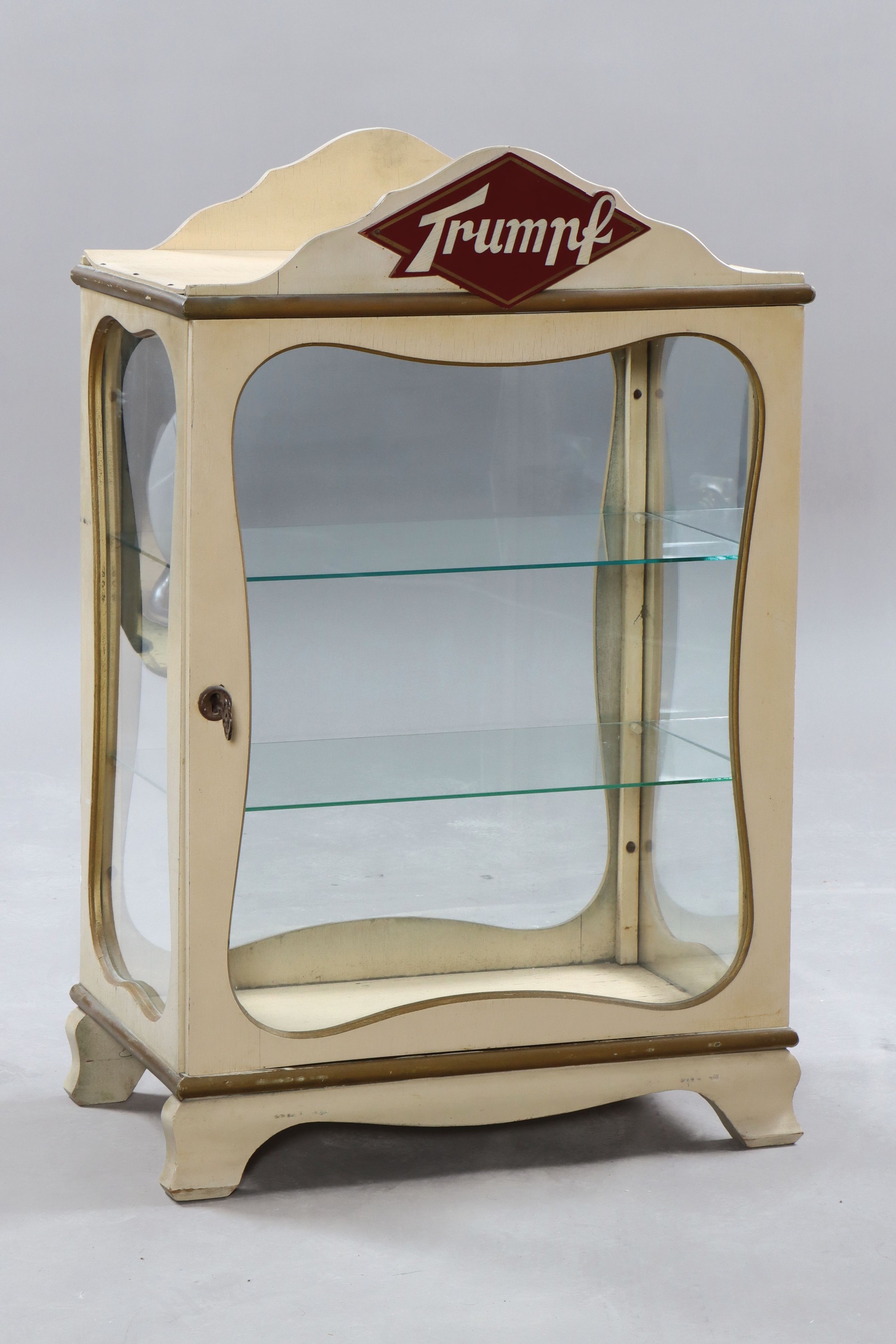 Verkaufsvitrine der Firma Trumpf, deutsch, 1950er Jahre, weiß lackiertes Holz bronzefarben abgesetzt, mittig oben SChriftzug, allseitig verglast, ...