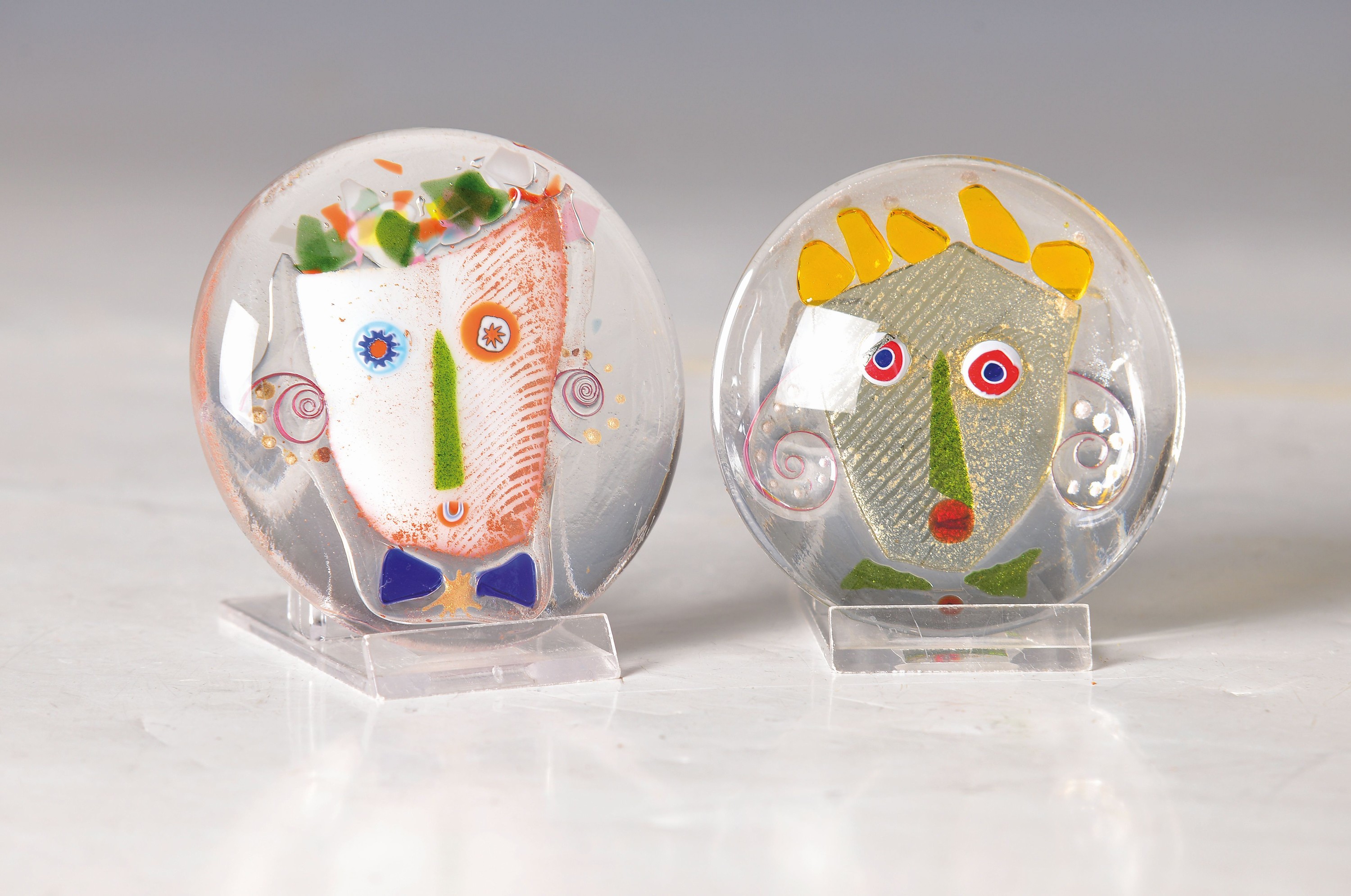 2 Paperweights, Michael Günther (geb. 1956), 2.H.20.Jh., farbloses Glas mit bunten Einschmelzungen in Form von Gesichtern, je signiert, D. je ca. ...