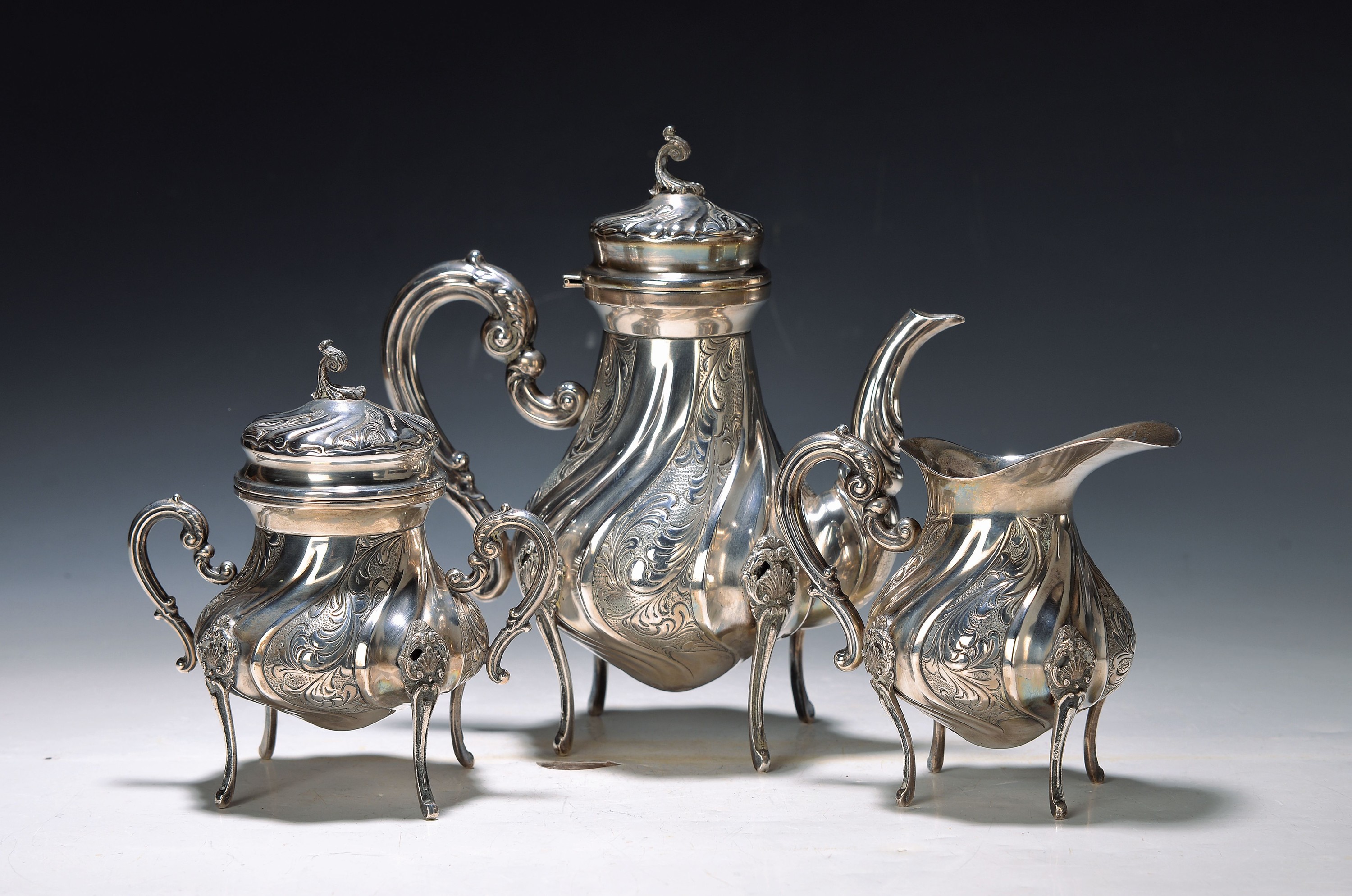 Kaffeeset, 800er Silber, 2. Hälfte 20. Jh., Kaffeekanne, Zuckerdose und Sahnegießer, au vier hohen Beinen, gedrehte Form, stil. Blätter, ...