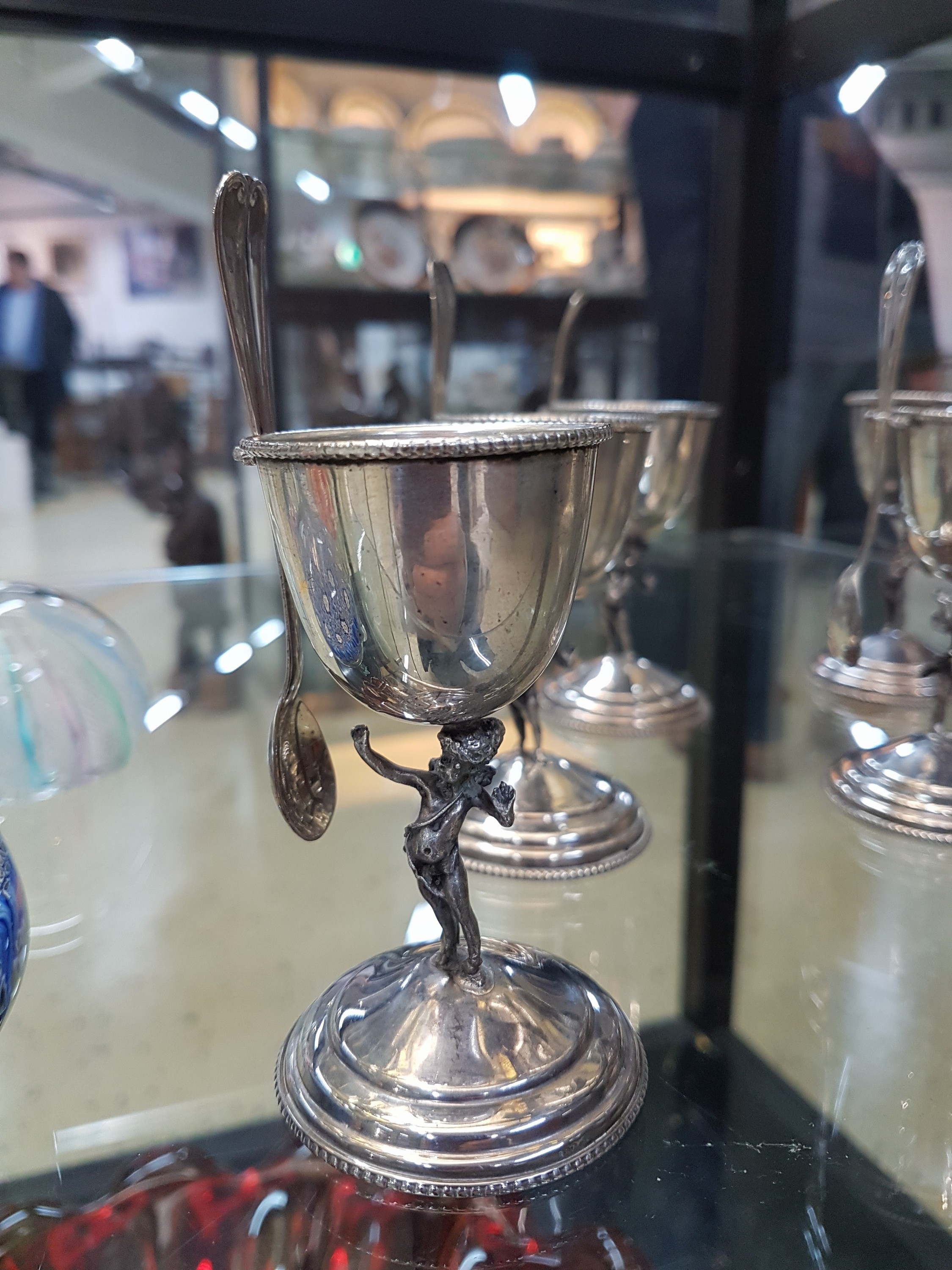 Detail b: 6 SIlber-Eierbecher mit Löffel, um 1900, 800er-Silber, mit vollplastischen Amoretten als Stil, H. ca. 9 cm, mit eingesteckten, Löffelchen 12 cm, am ...