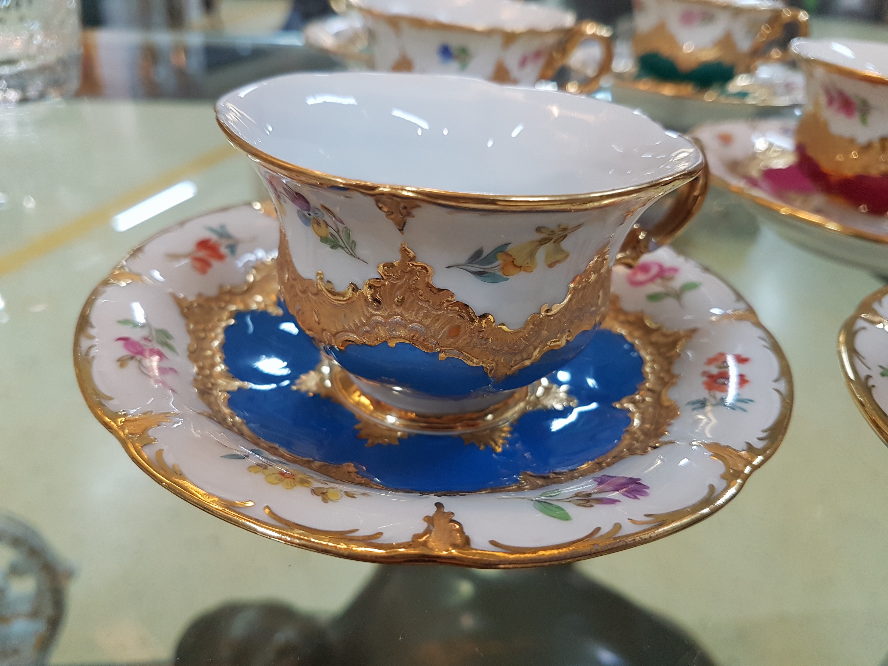 Detail b: 6 Mokkatassen, Meissen, B-Form, 20. Jh., versch. farbige Tassen mit gestreuten Blümchen, Matt- und Glanzvergoldung, mit Untertassen