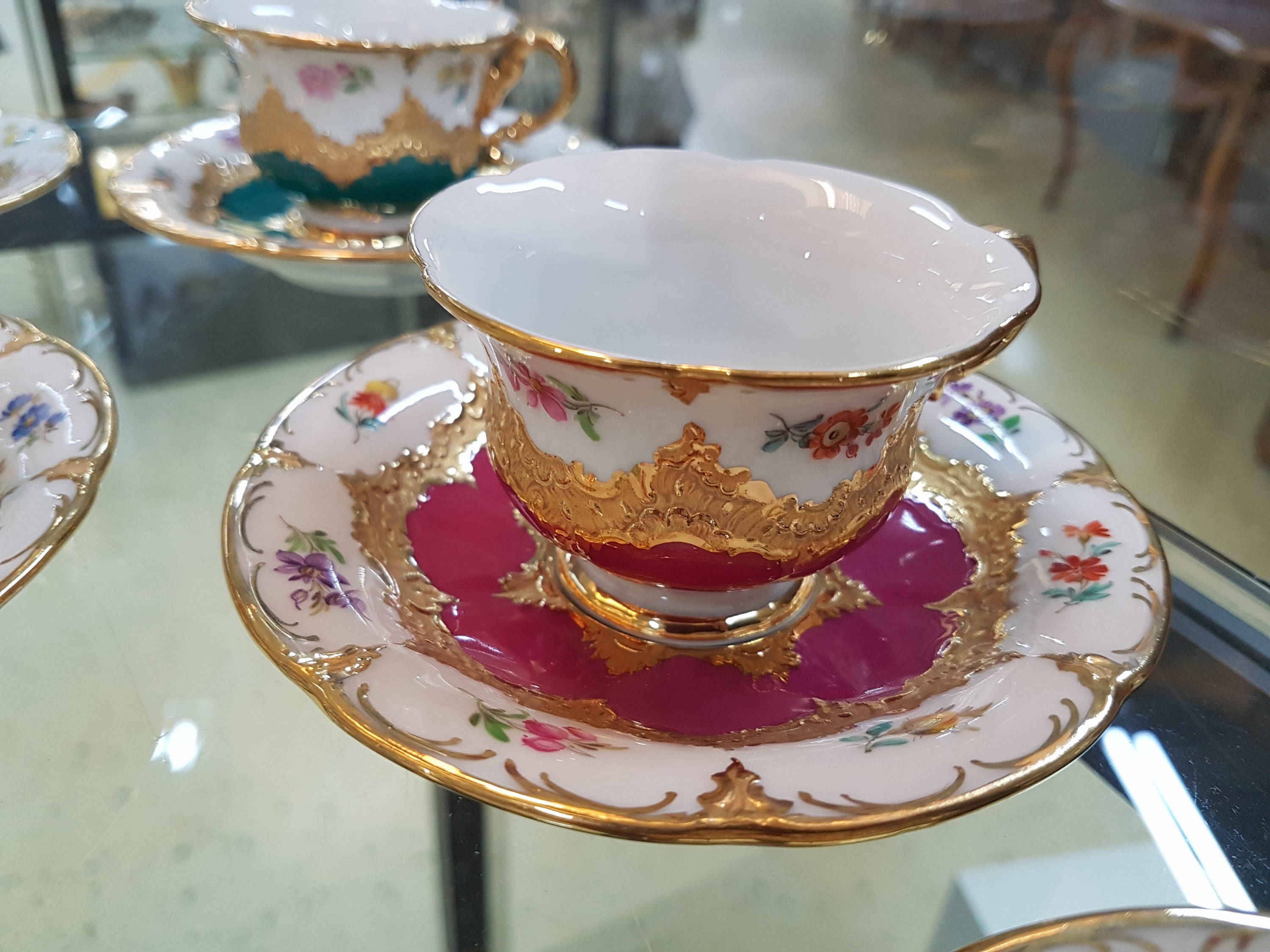 Detail d: 6 Mokkatassen, Meissen, B-Form, 20. Jh., versch. farbige Tassen mit gestreuten Blümchen, Matt- und Glanzvergoldung, mit Untertassen
