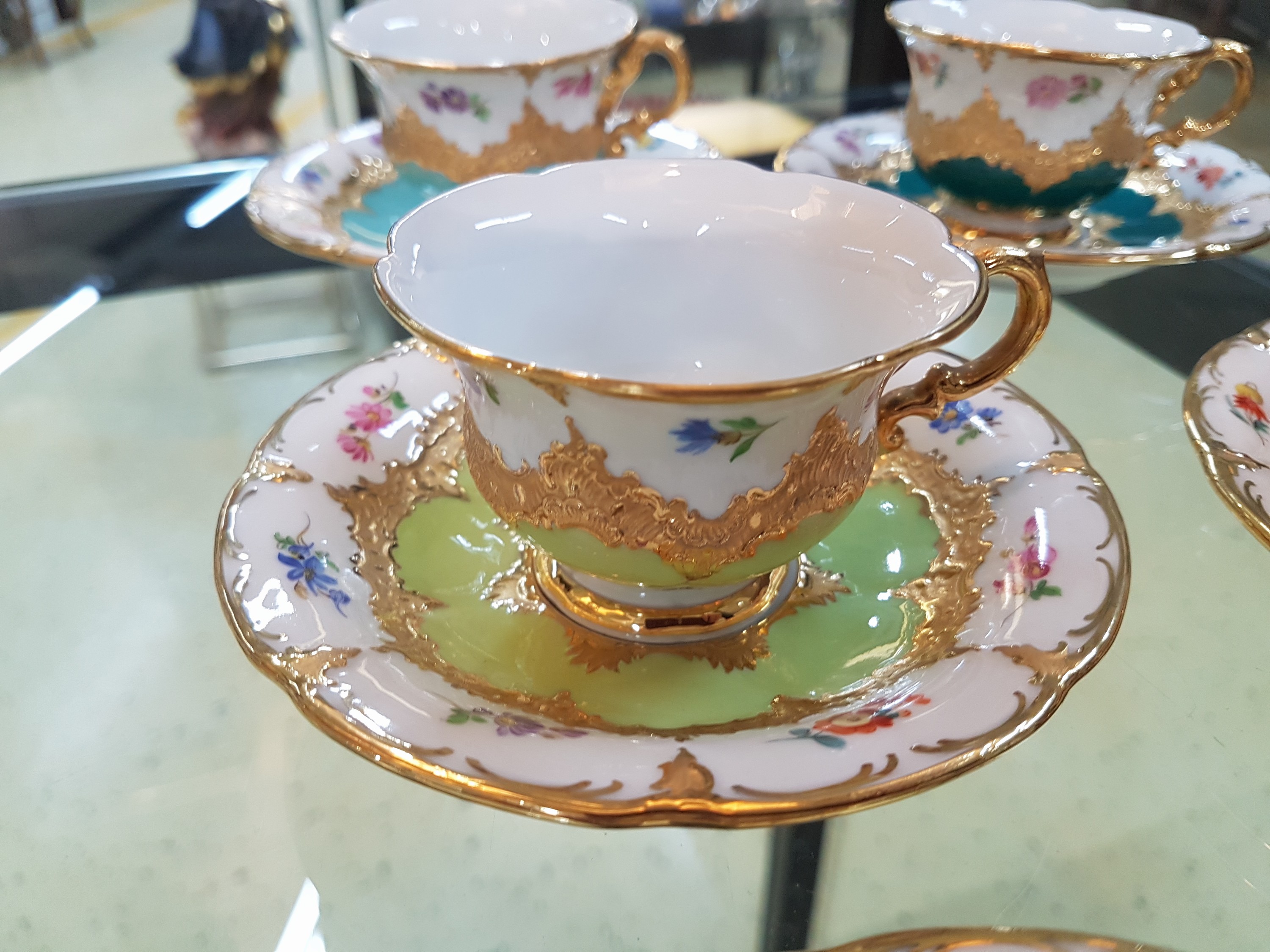 Detail e: 6 Mokkatassen, Meissen, B-Form, 20. Jh., versch. farbige Tassen mit gestreuten Blümchen, Matt- und Glanzvergoldung, mit Untertassen