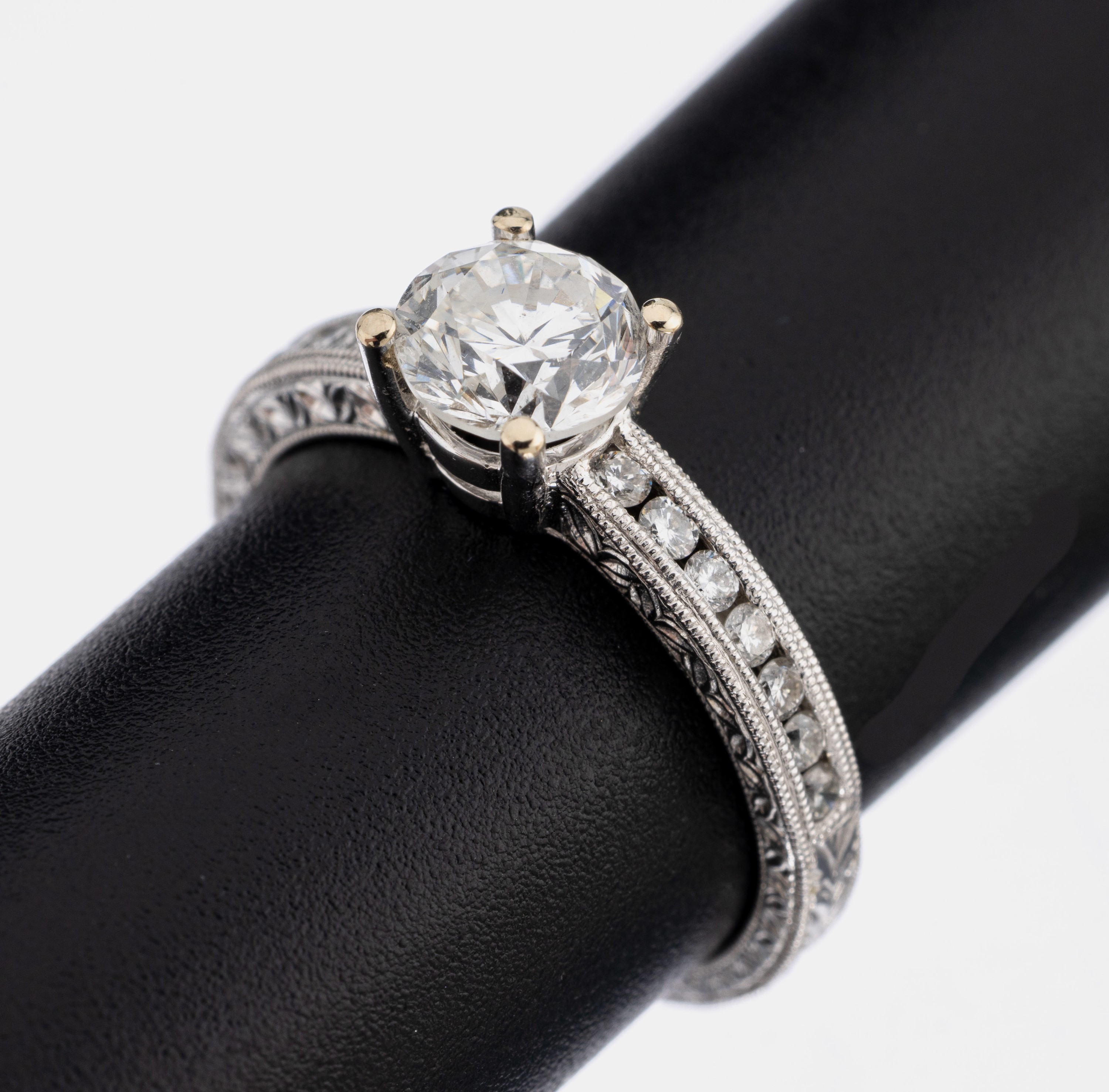 18 kt Gold Brillant-Ring, WG 750/000, mittig erhaben gefasster Brillant ca. 1.01 ct (grav.) Weiß/si, Ringschultern mit 14 Brillanten zus. ca. 0.23 ...