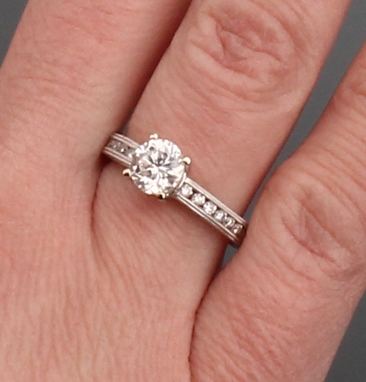 Detail e: 18 kt Gold Brillant-Ring, WG 750/000, mittig erhaben gefasster Brillant ca. 1.01 ct (grav.) Weiß/si, Ringschultern mit 14 Brillanten zus. ca. 0.23 ...