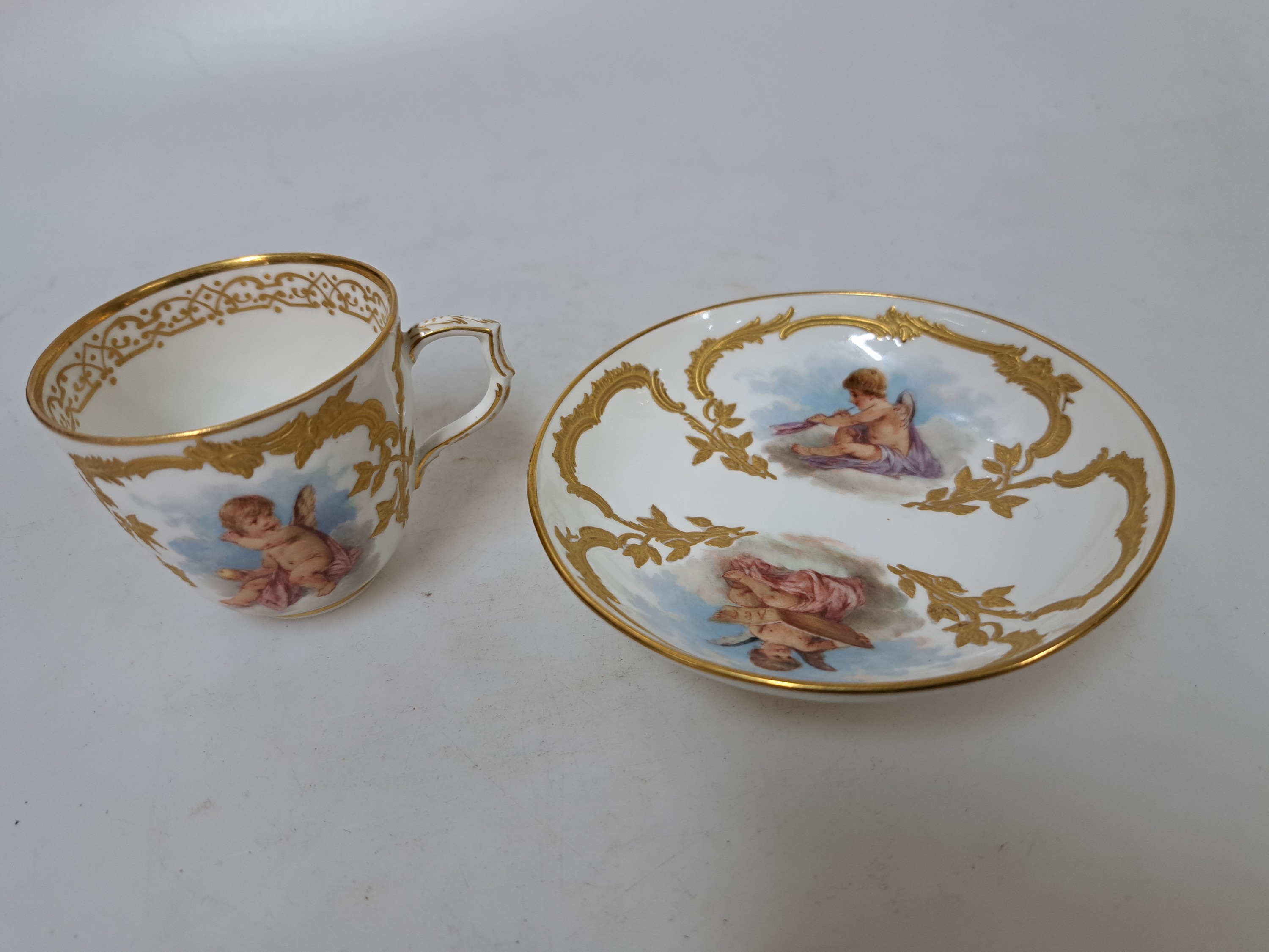 Detail e: Mokkatasse mit Untertasse, KPM Berlin, um 1900, Form Neuzierat, sog. fliegende Kinder, fein gemalte Putten mit verschiedenen Attributen in ...