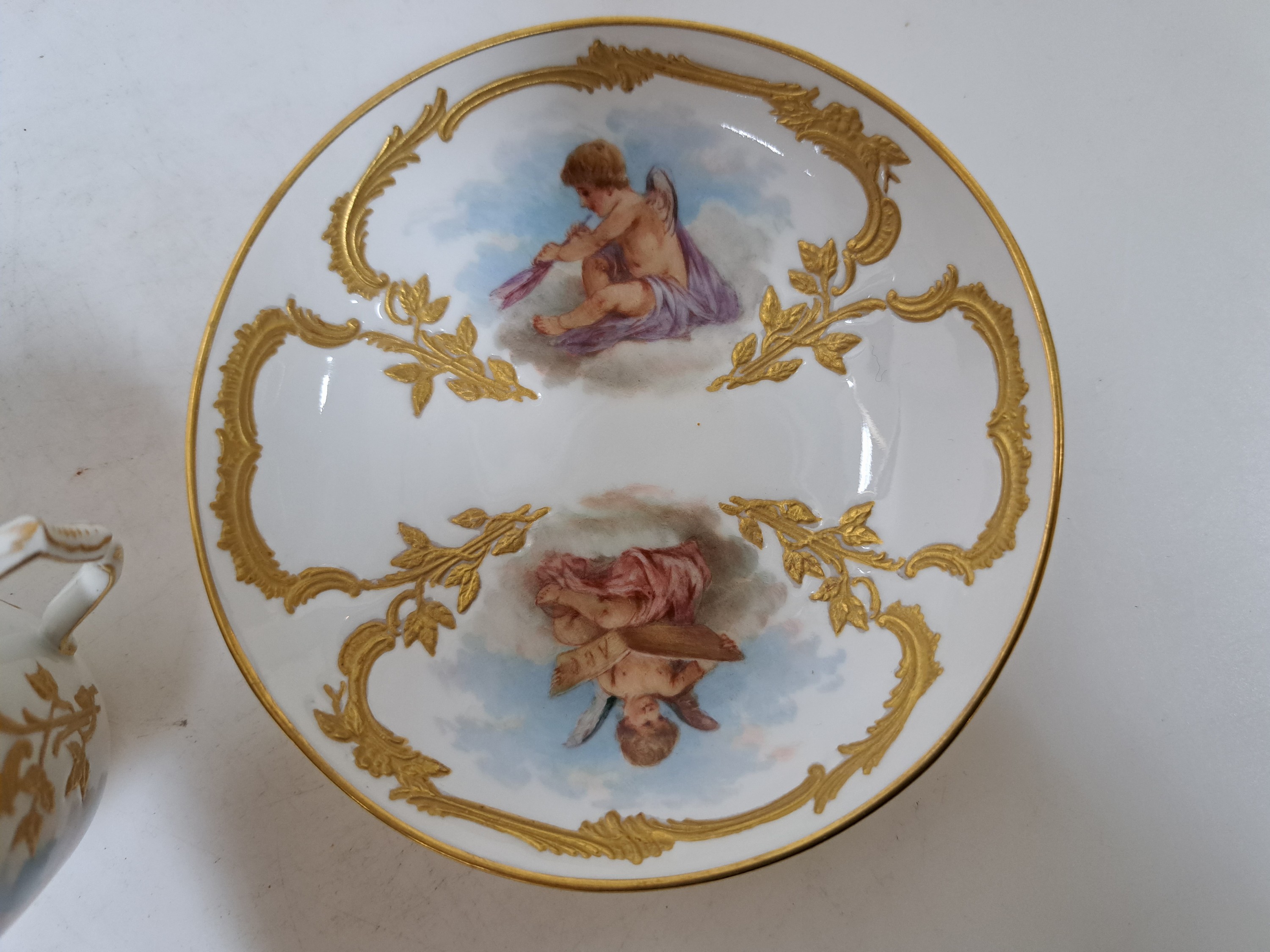 Detail g: Mokkatasse mit Untertasse, KPM Berlin, um 1900, Form Neuzierat, sog. fliegende Kinder, fein gemalte Putten mit verschiedenen Attributen in ...
