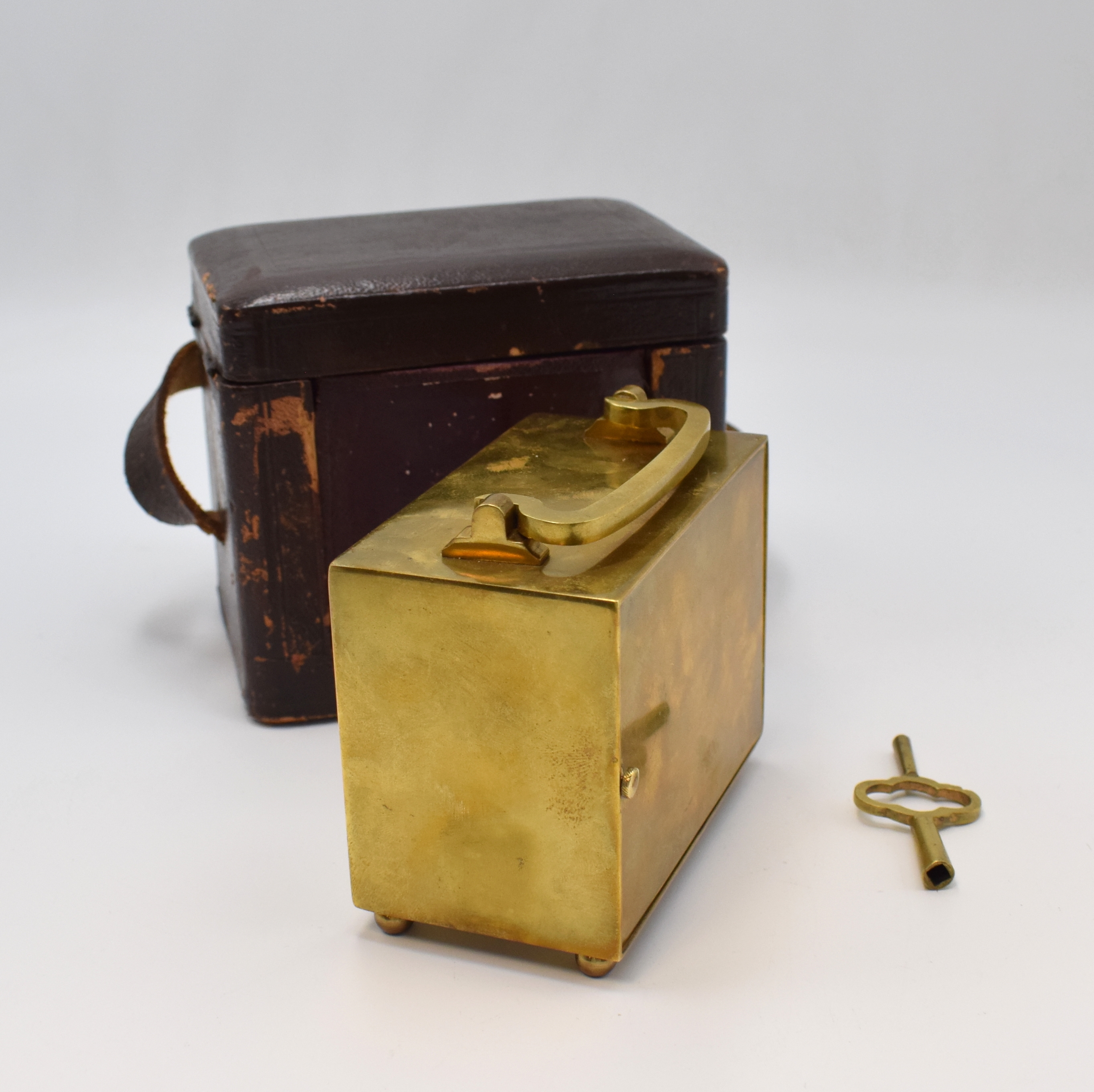 Detail c: Reiseuhr mit Wecker, Frankreich um 1920, Messinggeh. m. Tragegriff, vergl. orig. Transportbox u. Schlüssel, Emailzifferbl. besch., röm. Zahlen, ...
