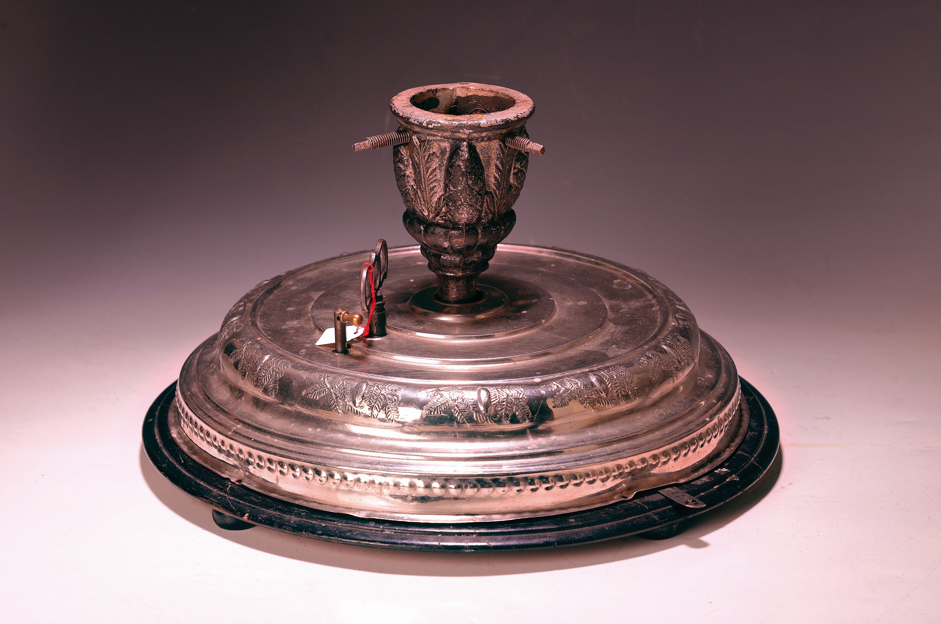 Christbaumständer mit Spieluhr, deutsch, um 1900, Holzplatte mit geprägtem Metallgehäuse, Dekor mit Tannenzweigen und Zapfen, manueller Wechsel ...