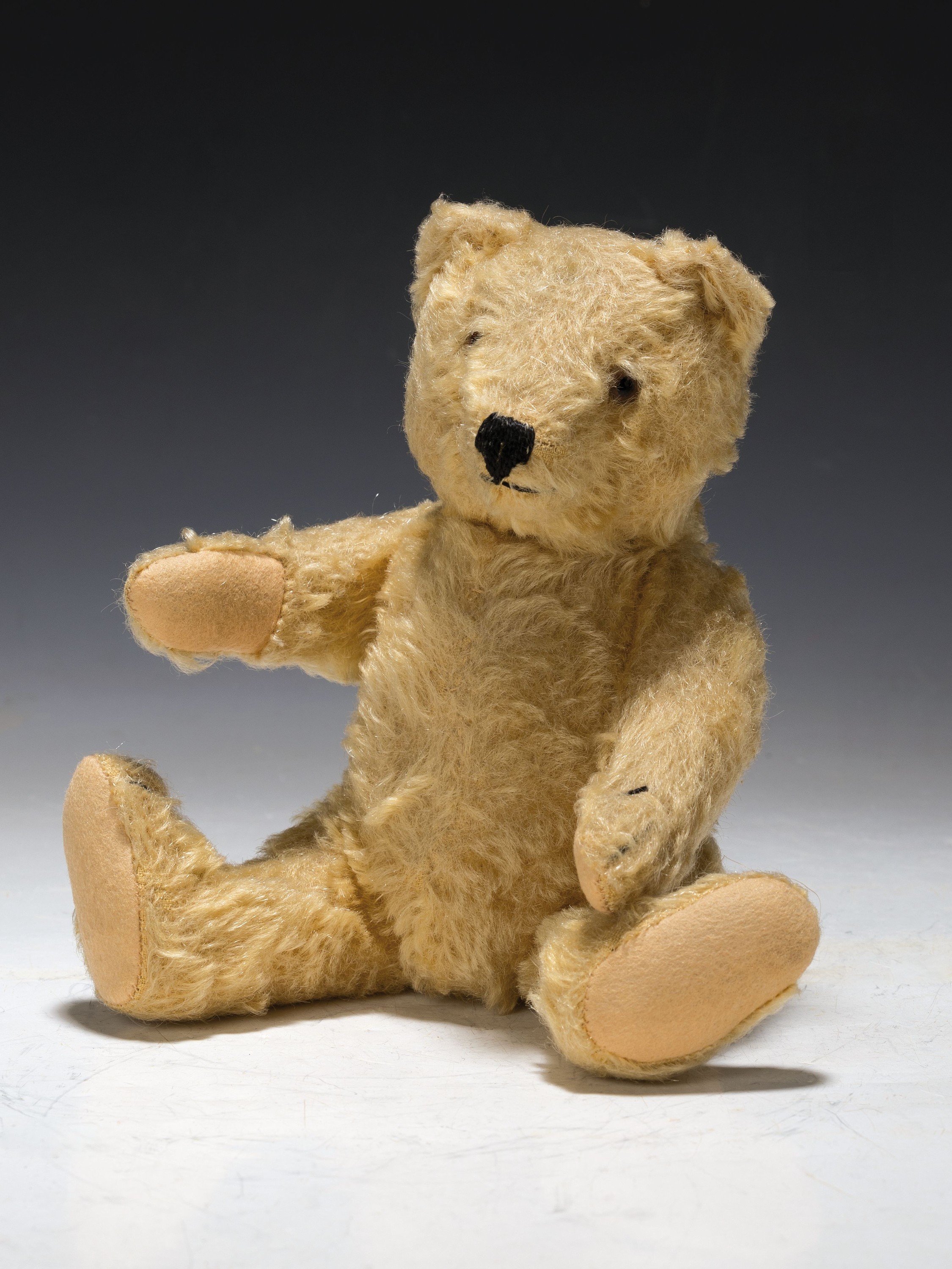 Kleiner Teddy, wohl Steiff, 1930er Jahre, blonder Mohairplüsch, kleiner Buckel, H.ca.22 cm, ohne Knopf u. Fahne, min. bespielt, lange Schnauze u. ...