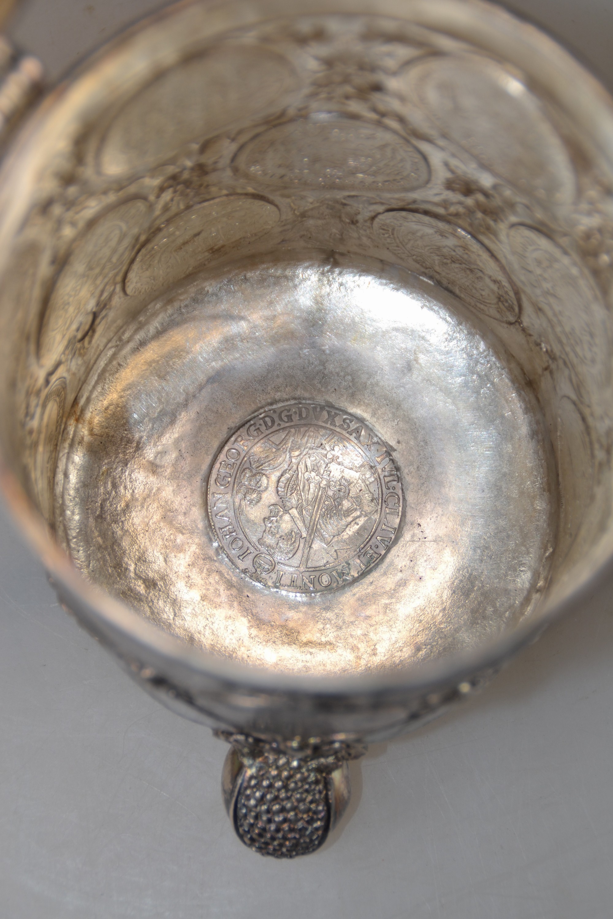 Detail k: Münzkrug, deutsch, wohl Hanau, Mitte 19.Jh., Silber, auf drei Kugelfüßen stehend, Münzreliefs in Wandung, Deckel und Boden, Griff in Form eines ...
