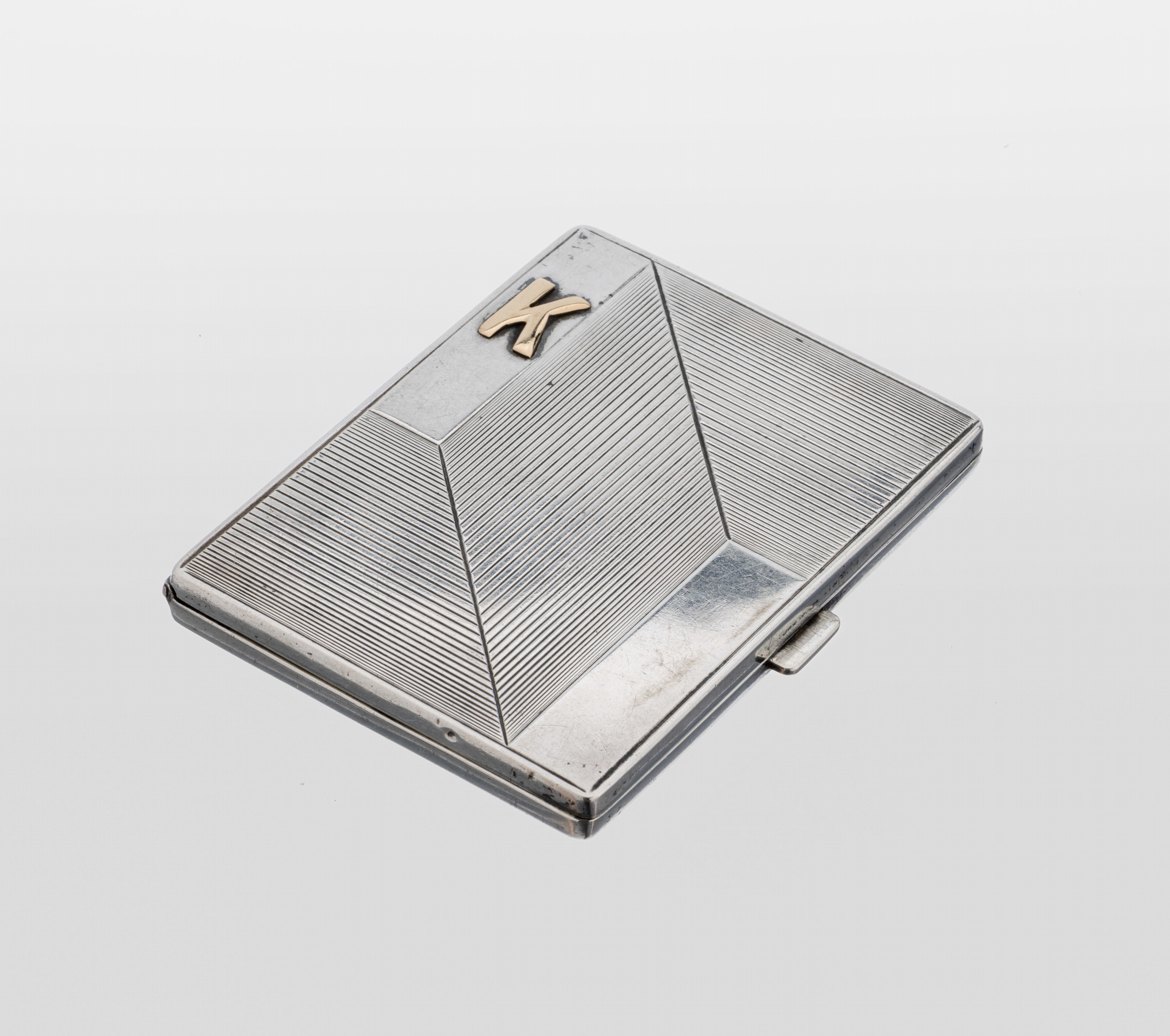 Zigarettenetui, um 1930, 900er Silber, geometrisches Rillendekor, aufgelegtes K aus GG, innen vergoldet, ca. 8 x 6 cm, Haltebänderfehlend, innen ...