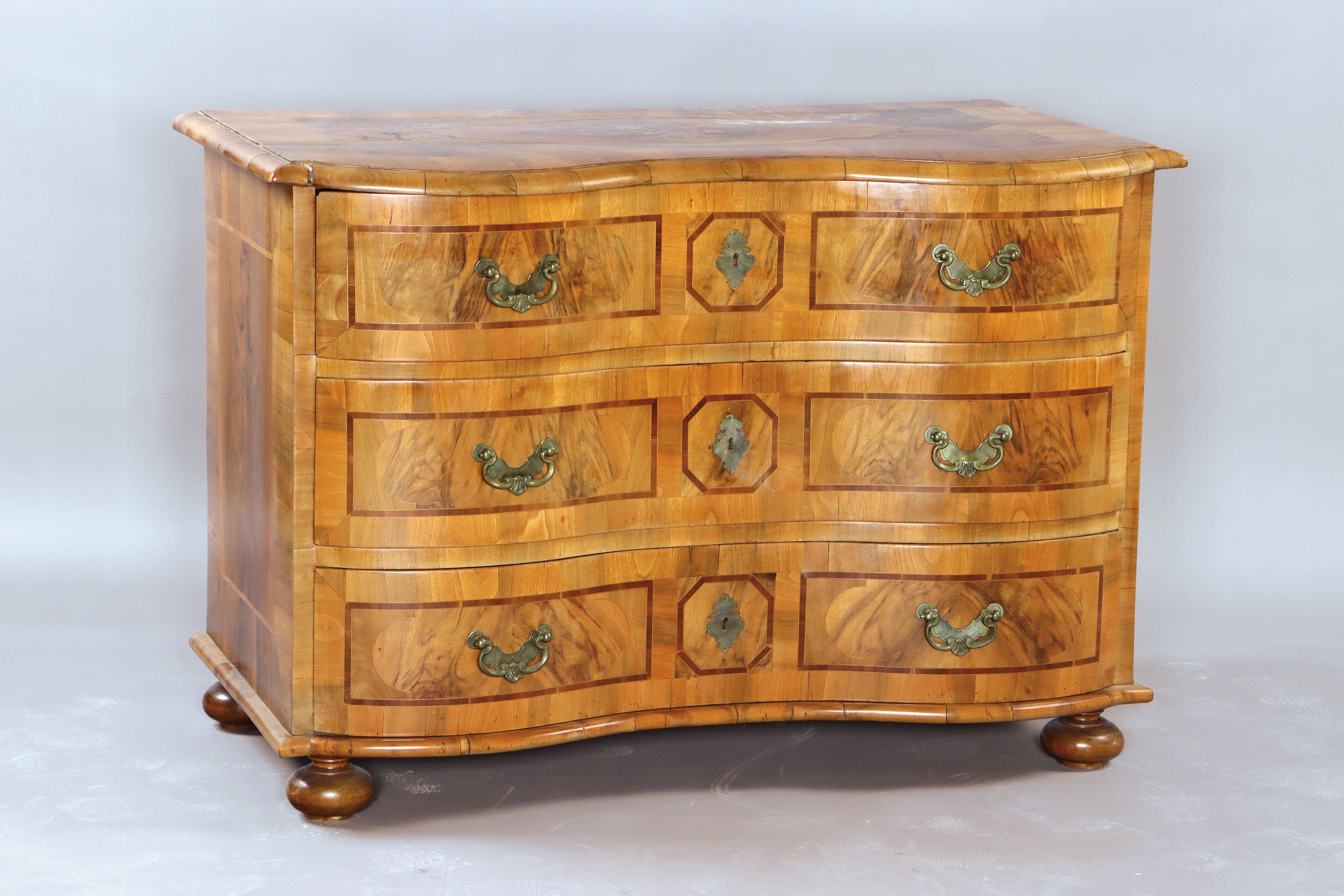 Kommode, Barock, Mitte 18. Jh., Nussbaumfurnier, doppelt geschweift, drei Schubladen, Platte mit Blumenintarsien, Schubladen mit Bandeinlagen ...