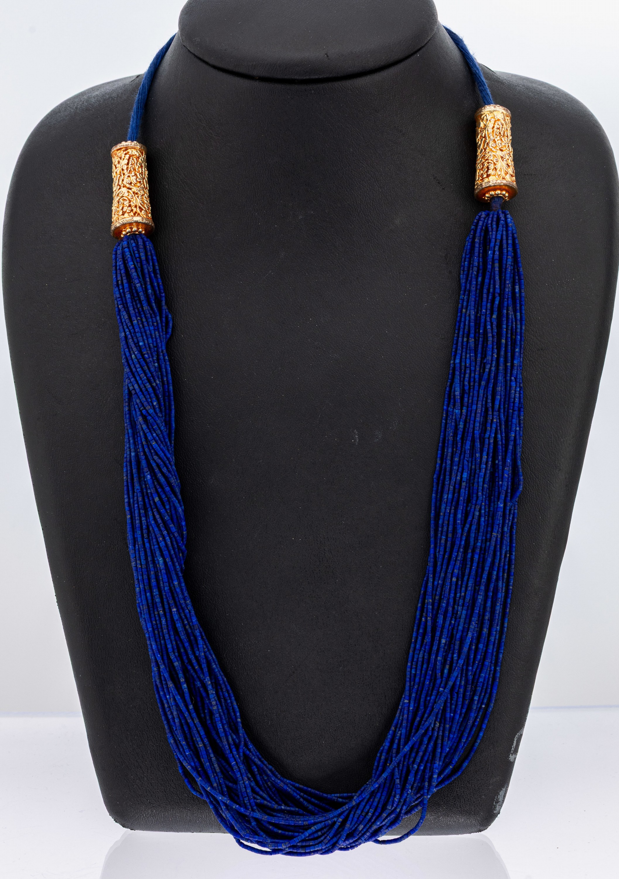 50 rhg. Lapislazuli-Collier, Monturen Silber vergoldet, Lapislazuli von feiner Farbe, Enden aus blauem Band (L. 18 cm), Gesamtl. ca. 60 cm, Ende ...