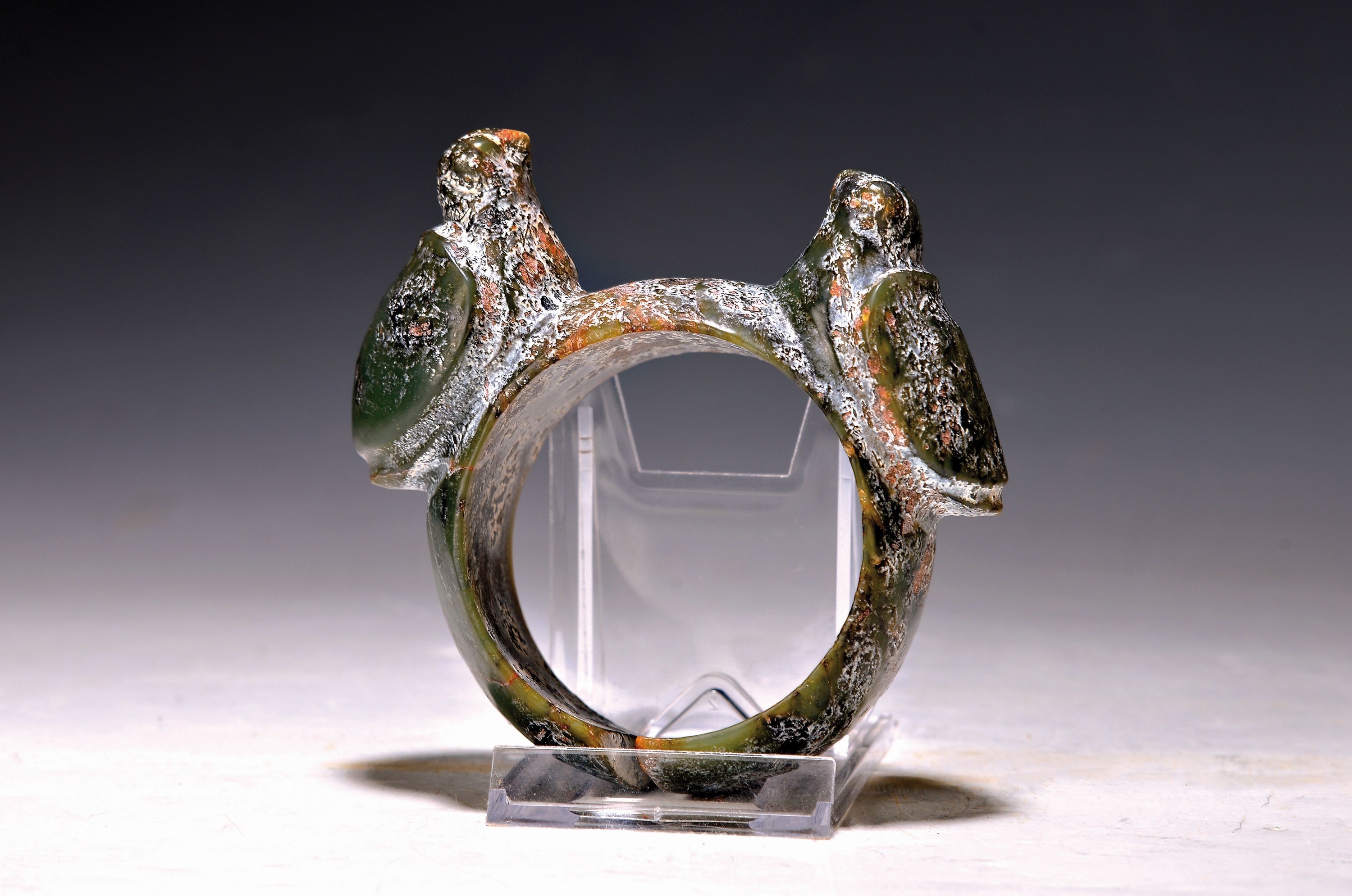 Armreif aus Jade, nach altem Vorbild (Hongshan?), China, 20.Jh., grüne Jade mit Ausblühungen, runder Reif mit einem Paar aufgesetzter Vögel, ...